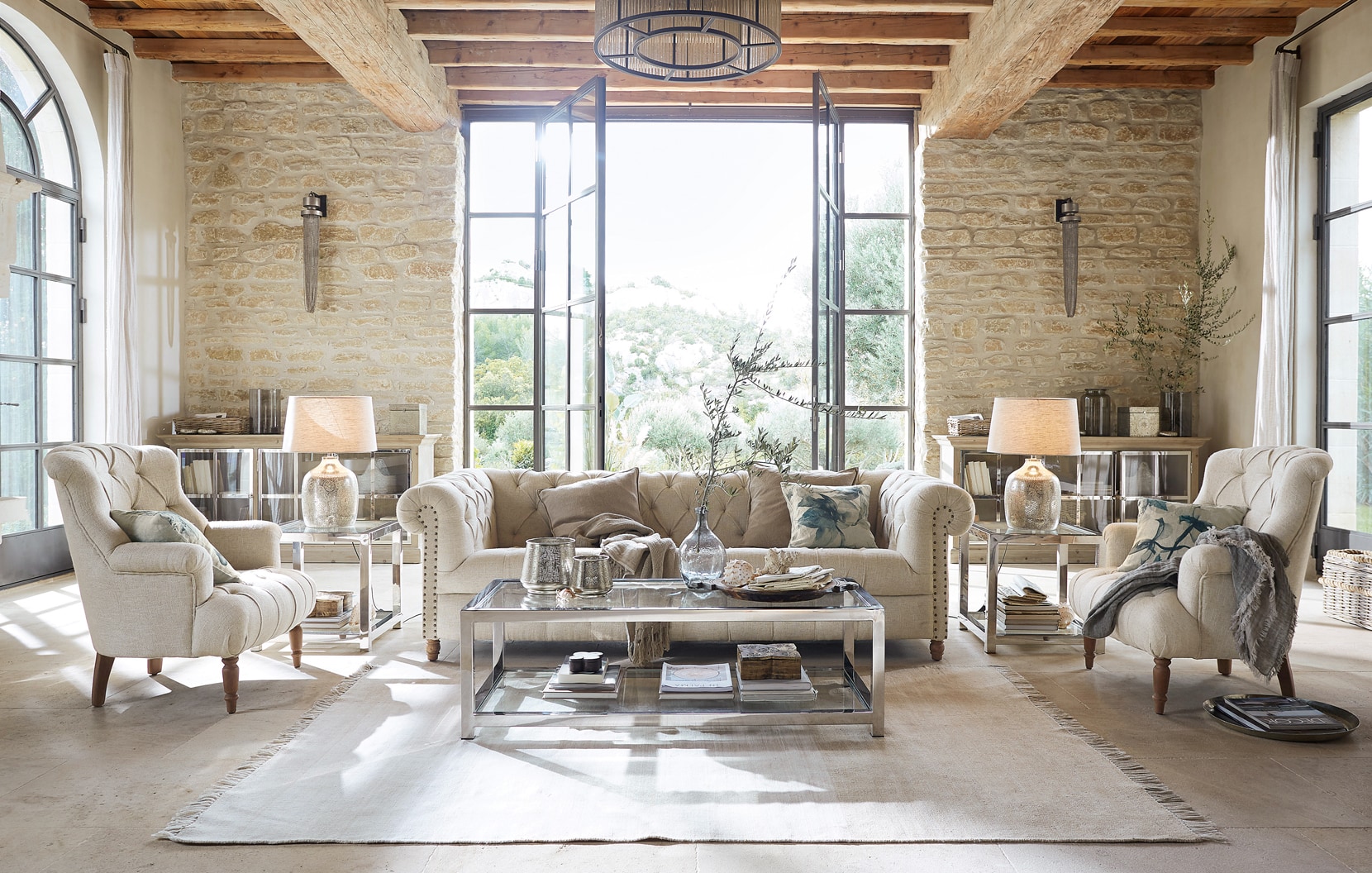 Klassisch elegantes Wohnzimmer mit beigem Sofa, Sesseln, Glastisch und natürlichen Materialien.