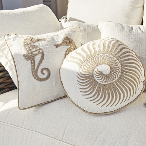 Dekorative Baumwollkissen in Creme mit Seepferdchen- und Muschelmotiv auf hellem Sofa