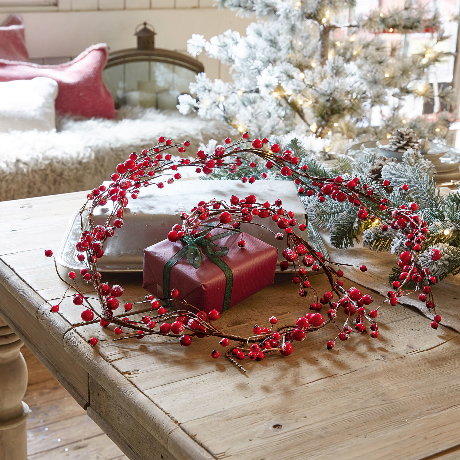 Girlande Rimont Dekorativer Kranz aus roten Beeren auf Holztisch mit Geschenk und Weihnachtsdekoration
