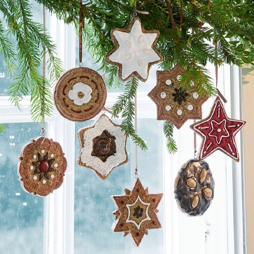 Weihnachtsschmuck aus natürlichen Materialien in Stern- und Kreisformen, an einem Tannenzweig hängend
