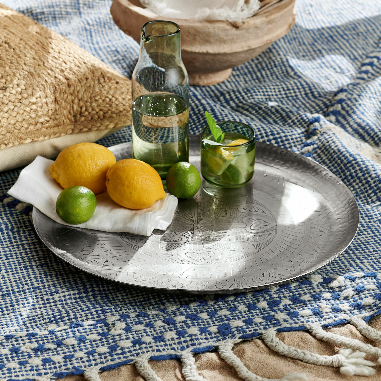 Rundes Metalltablett mit Gravur auf blau-weißem Plaid mit Zitronen und Limetten
