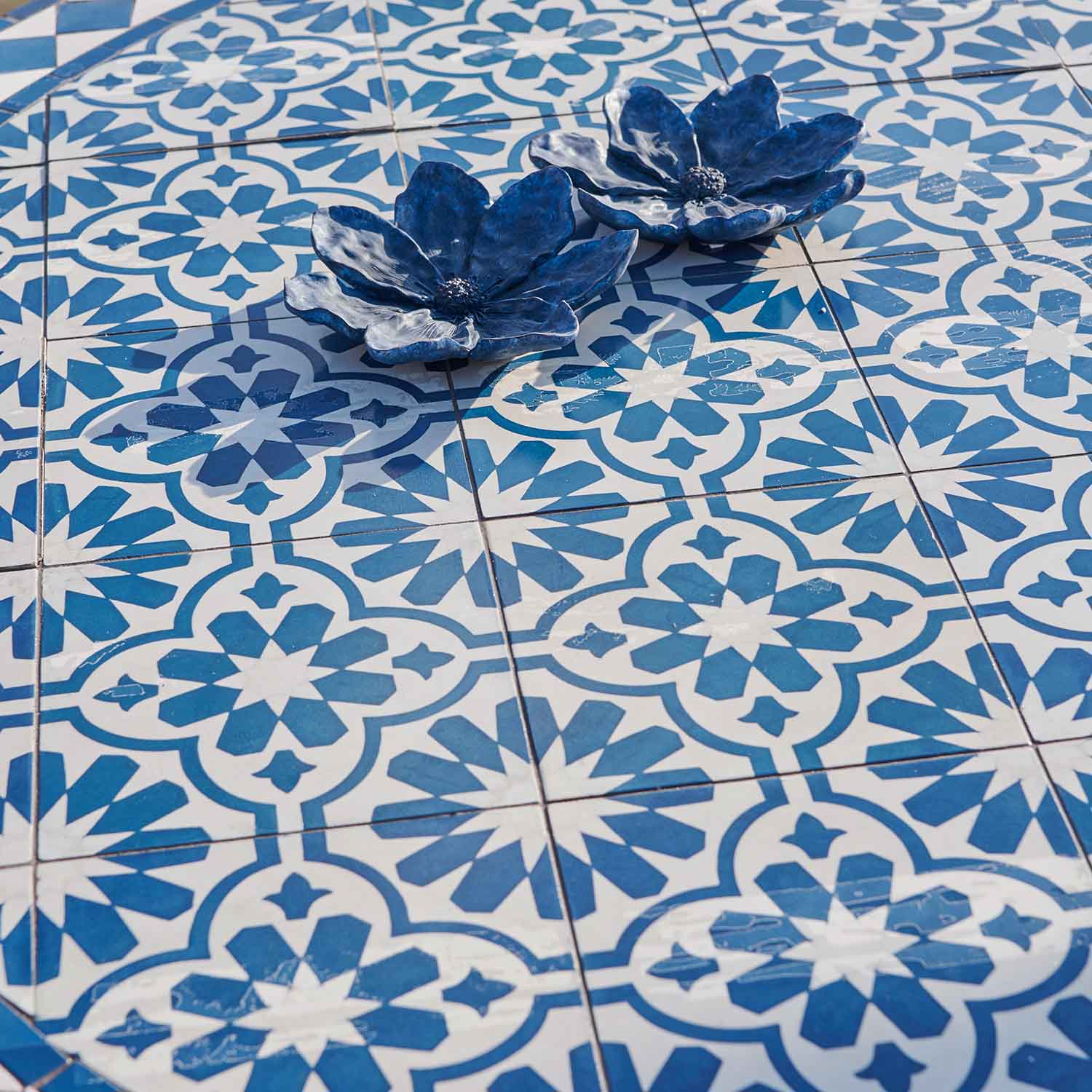 Blaue Keramikblumen auf weiss-blauen gemusterten Fliesen, elegante Wohnraumdekoration