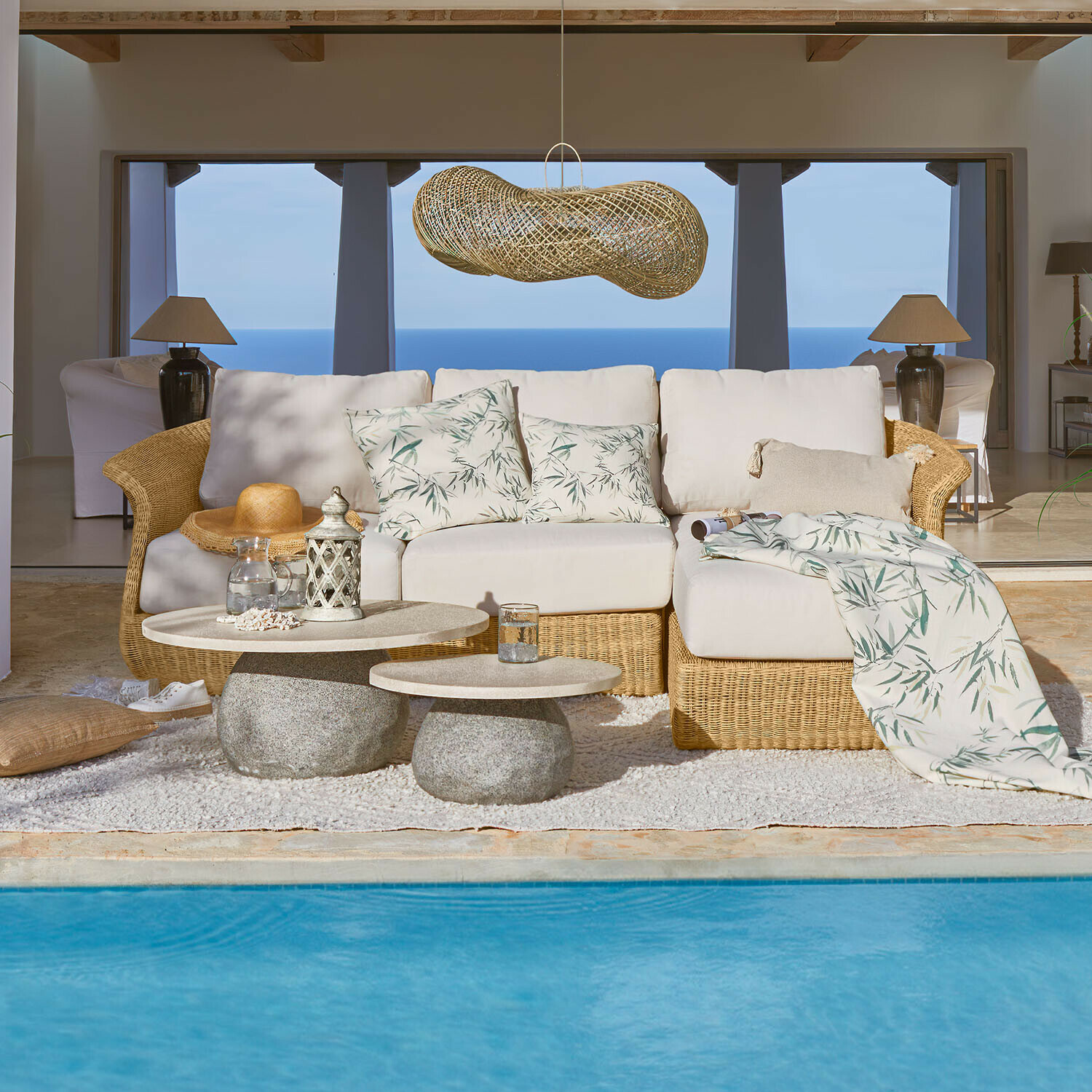 Sofa Cassianas Bequeme Rattan-Sofa mit hellen Kissen mit Blattmuster am Pool mit Meerblick