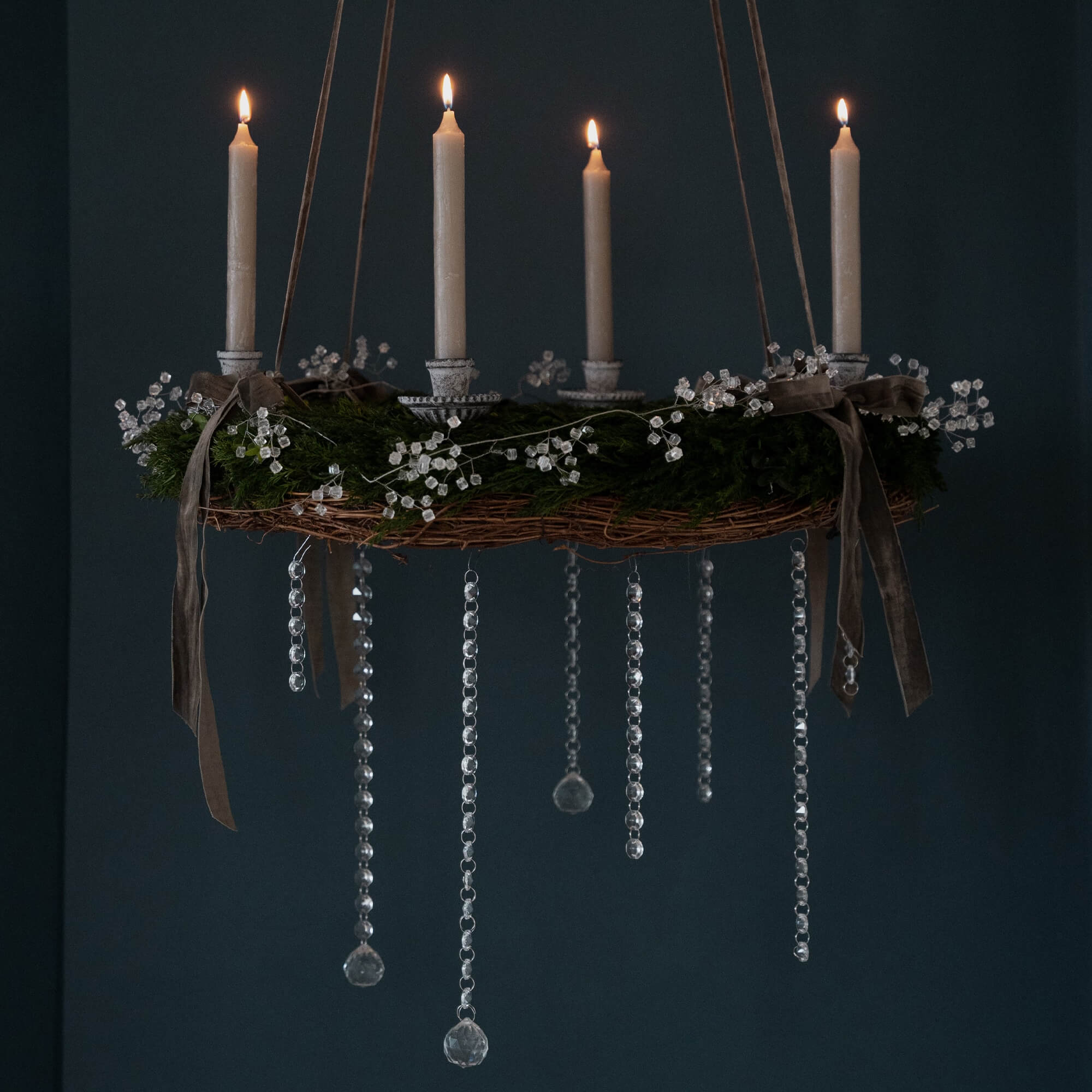 Hängender Adventskranz mit grünen Zweigen, weissen Kerzen und Kristallanhängern für festliche Dekoration