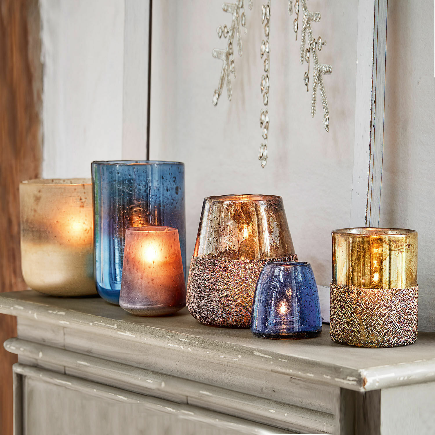 Set aus blauen und goldenen Glaswindlichtern auf Kommode, stilvolle Wohnraumdekoration