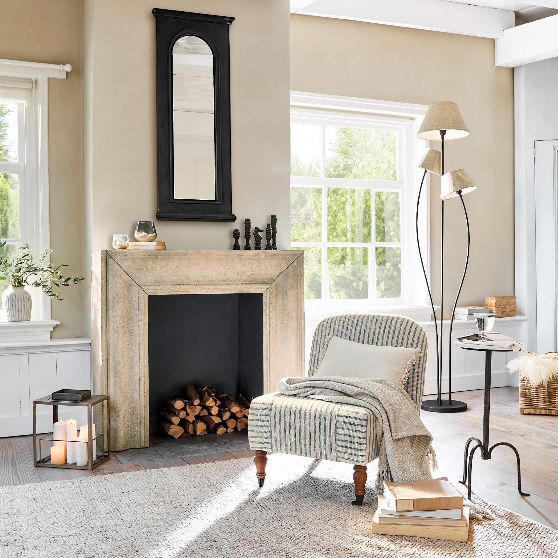 Gemütliches Wohnzimmer mit beigem Cheminée, schwarzem Spiegel und gestreiftem Vintage-Sessel