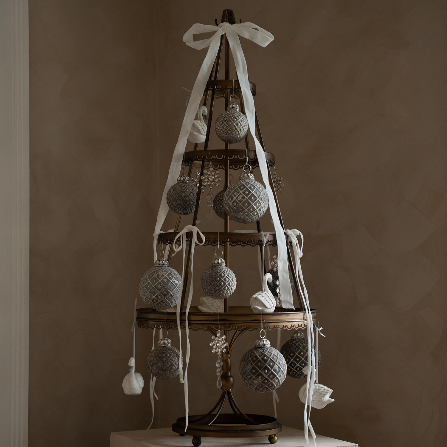 Dekorativer Metall-Weihnachtsbaum mit grauen Kugeln und weissen Bändern im Vintage-Stil