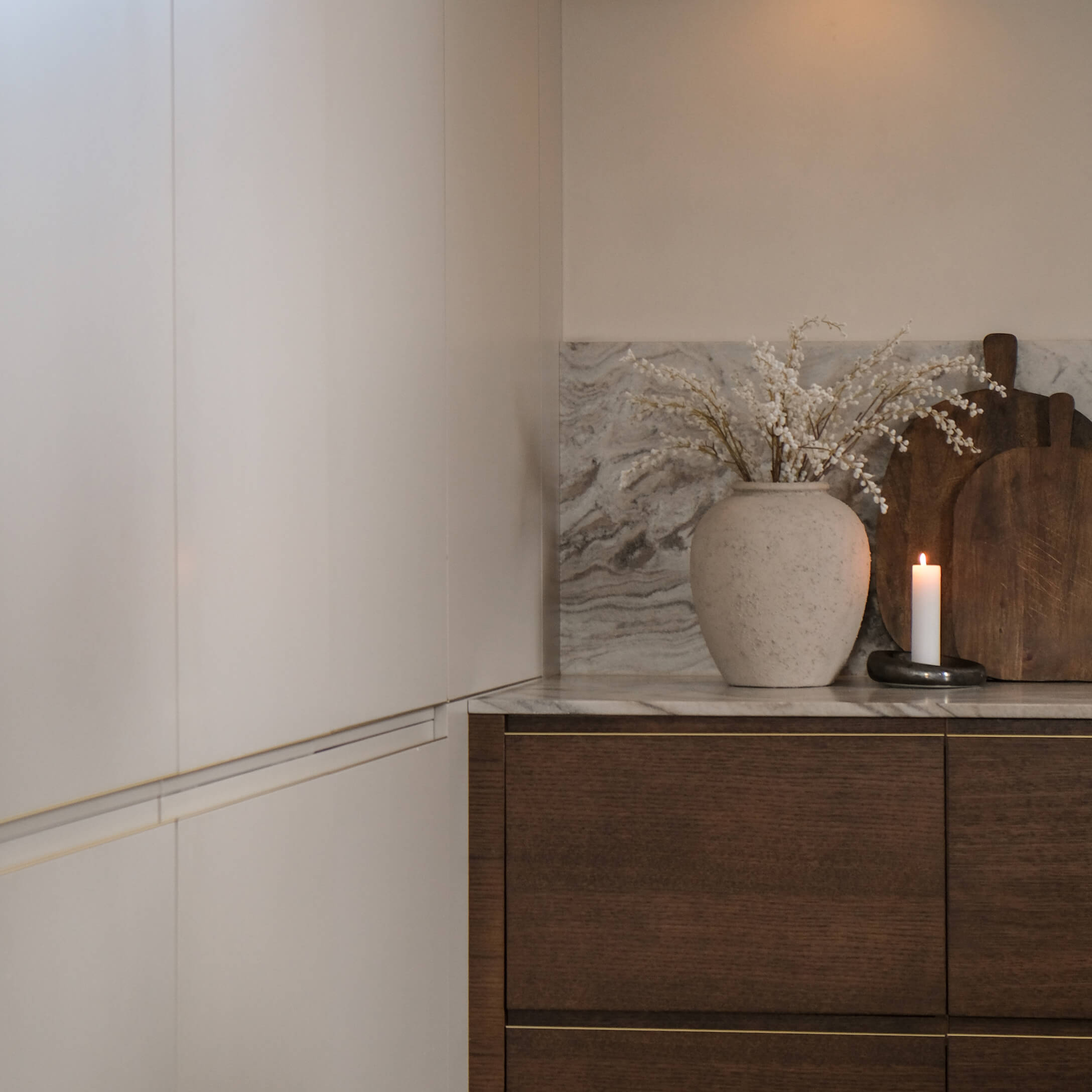 Küche mit weissen Schränken, Marmorarbeitsplatte, dekorative Vase mit weissen Blüten und brennender Kerze
