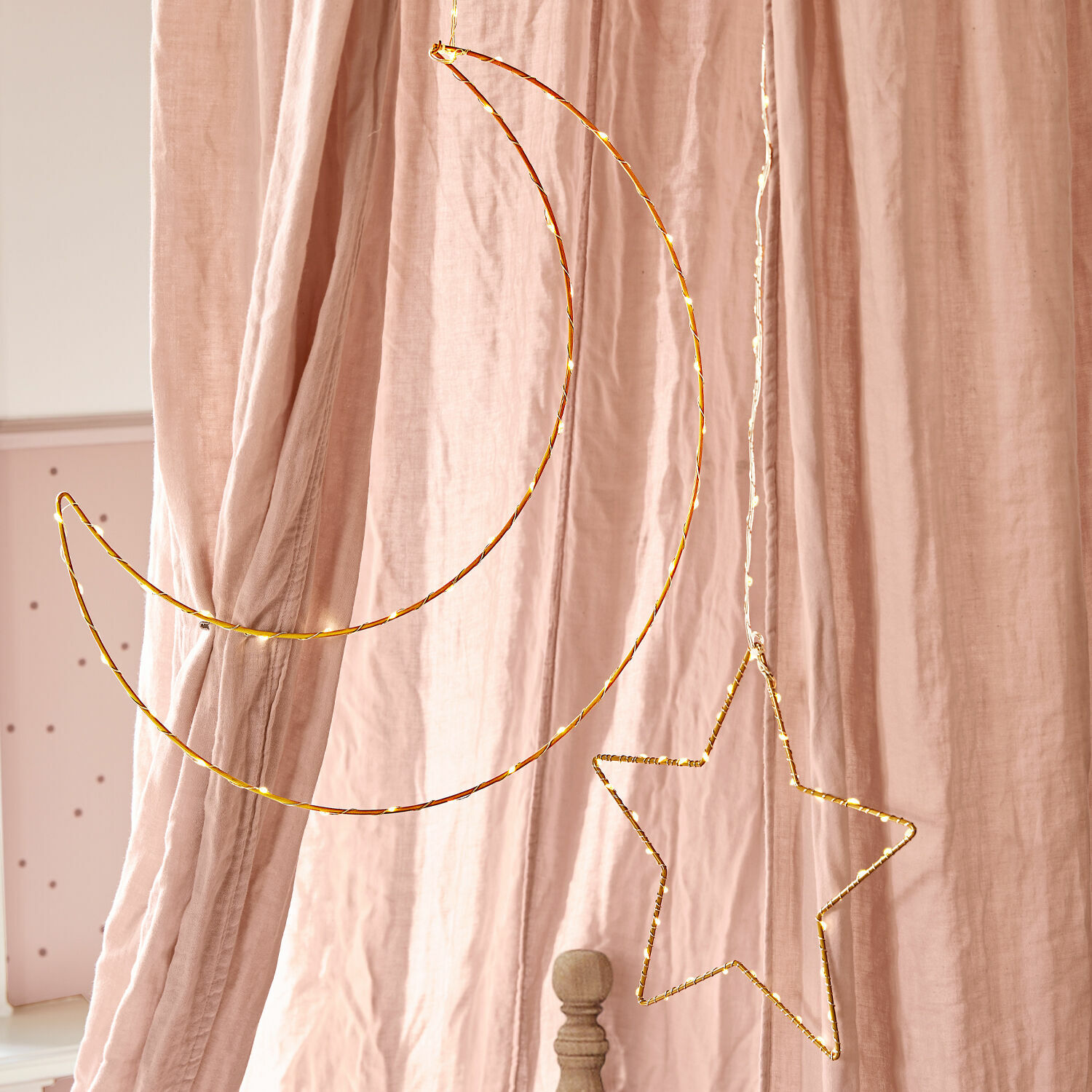 LED-Leuchtdeko 2er Set Padden Hängende Dekoration aus goldenem Metalldraht in Mond- und Sternform vor rosa Vorhängen