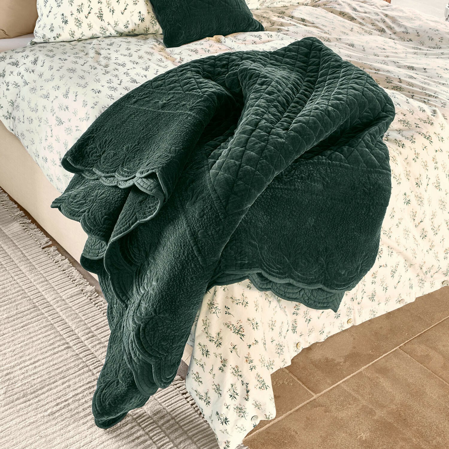 Quilt Lunévois Dunkelgrüner, gesteppter Überwurf aus weichem Stoff auf Bett mit hell geblümter Bettwäsche