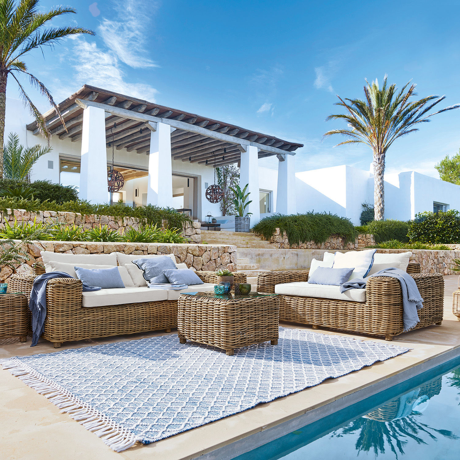 Sitzgruppe Camas Gartenmöbel-Set aus natürlichem Rattan mit cremefarbenen Polstern am Schwimmbadrand