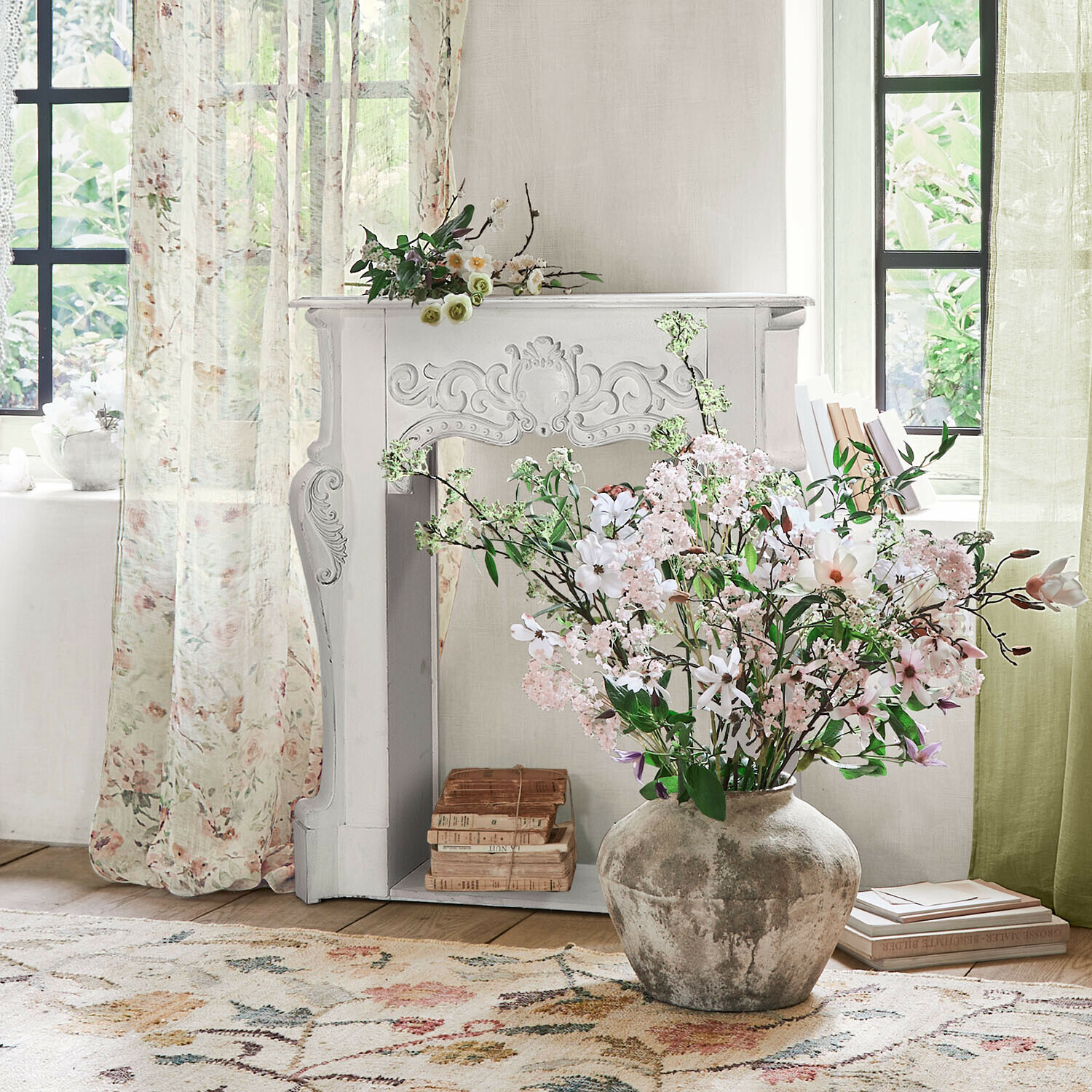 Kaminkonsole Emporia Große graue Keramikvase mit rosa und weißen Blumen vor hellem Raum mit dekorativem Kamin
