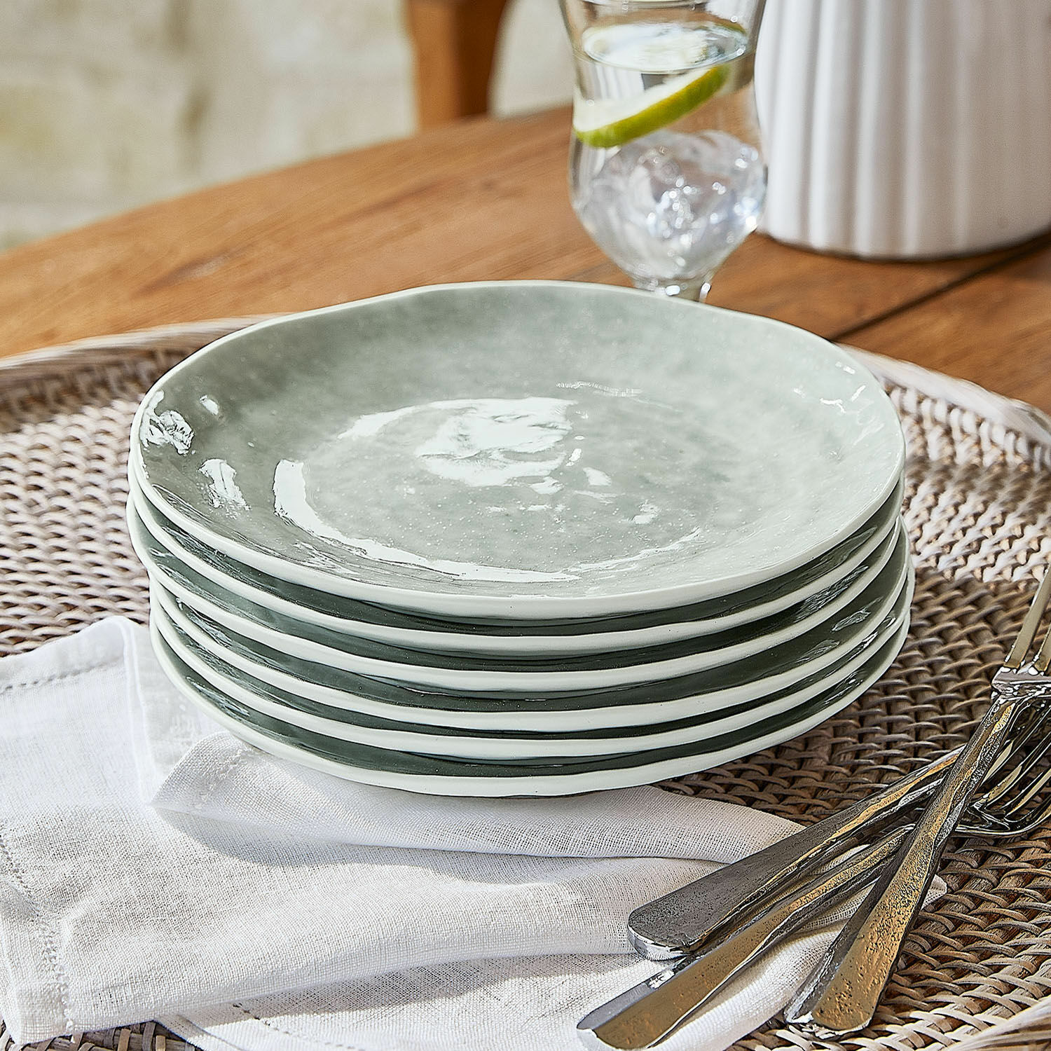 Sechser-Set grauer Keramikteller auf geflochtenem Tablett mit Metallbesteck