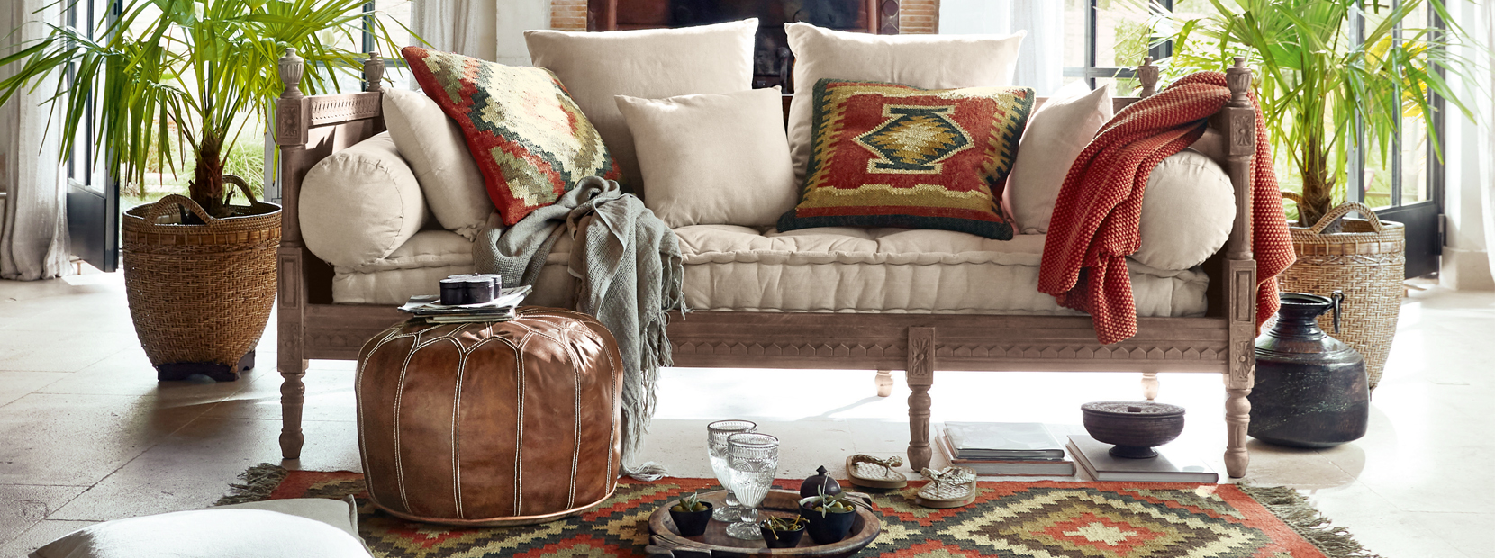 Helles Sofa mit cremefarbenen Kissen und orientalischen Mustern auf den Kissen und dem Teppich im Wohnzimmer