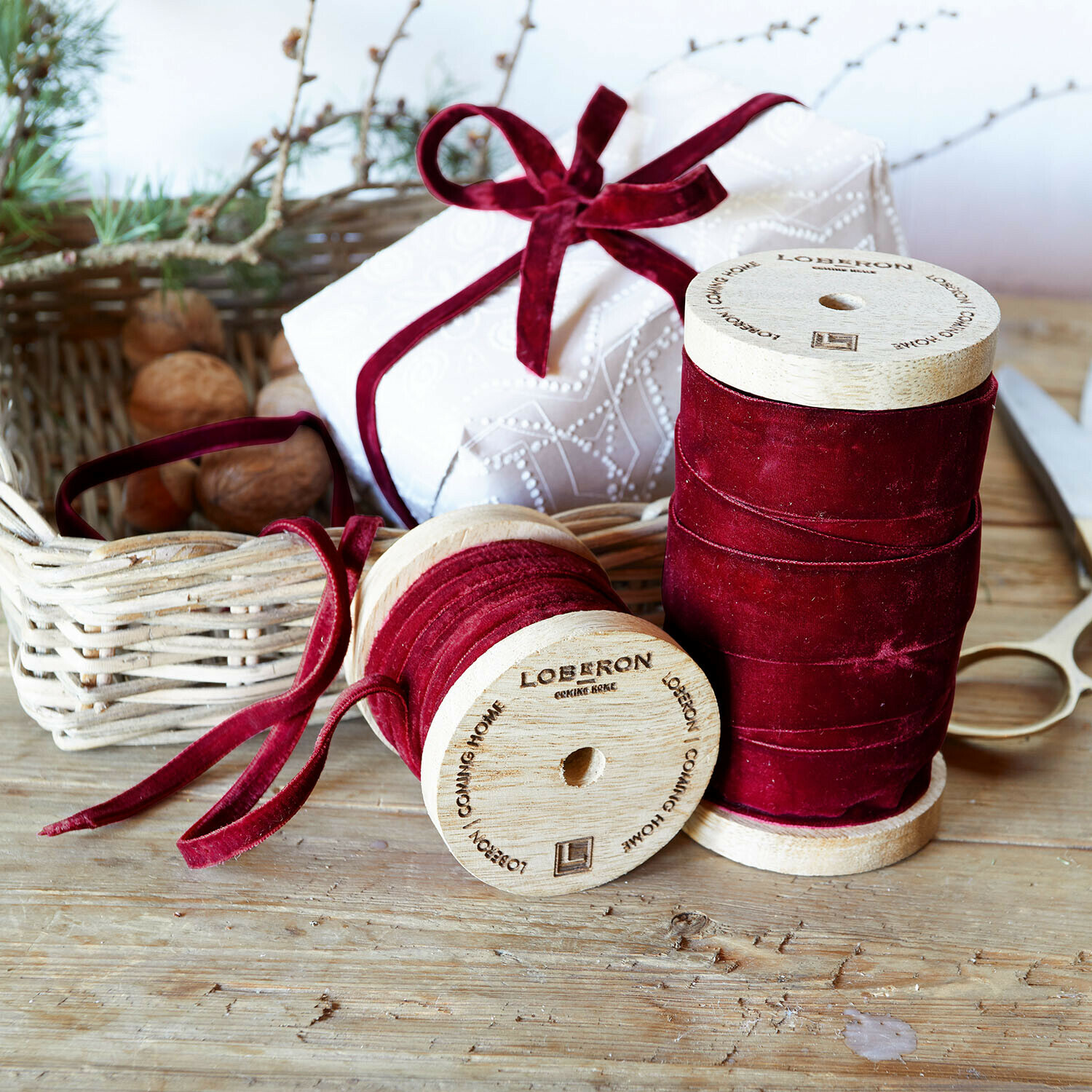 Samtband 2er Set Liandis Zwei Holzspulen mit bordeauxrotem Samtband auf Holztisch mit Schere und Geschenkverpackung