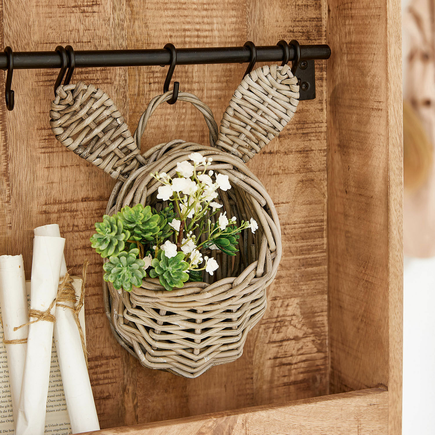 Korb Frances Hängender Korb aus Rattan in Kopf- und Ohrenform, dekoriert mit grünen und weissen Blumen