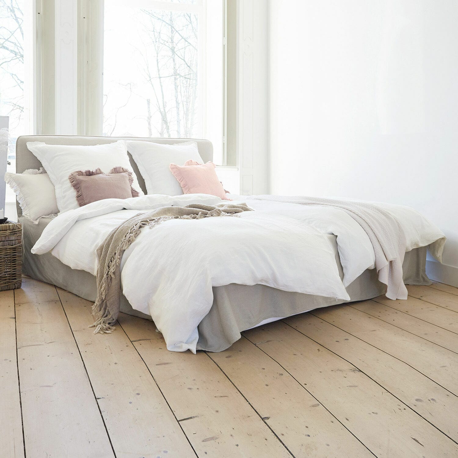 Bett Aubrianne Hellgraues Polsterbett mit weisser Bettwäsche und pastellfarbenen Kissen in hellem Schlafzimmer