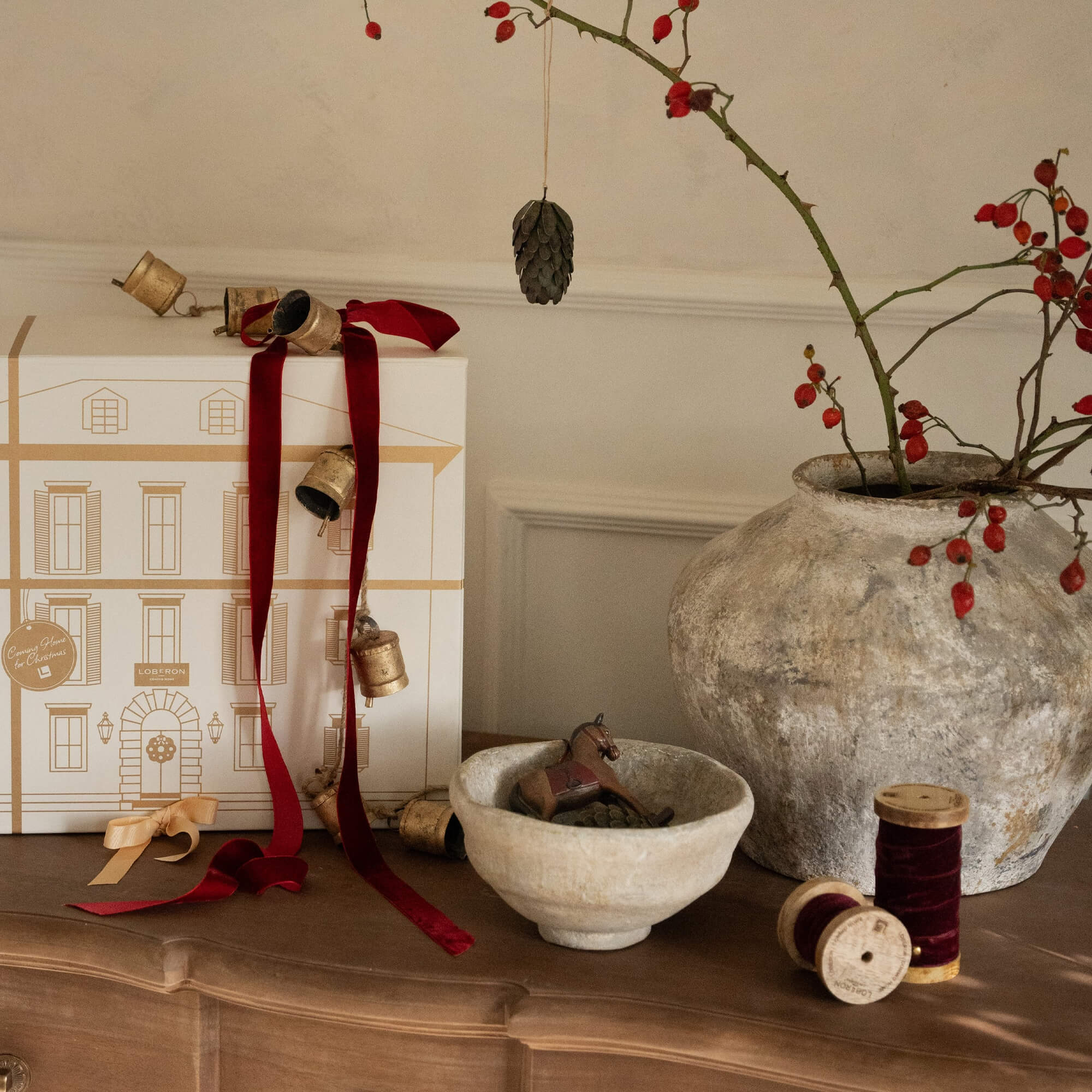 Weihnachtliche Dekoration mit roten Bändern, Keramikschale und grosser Vase mit roten Beeren