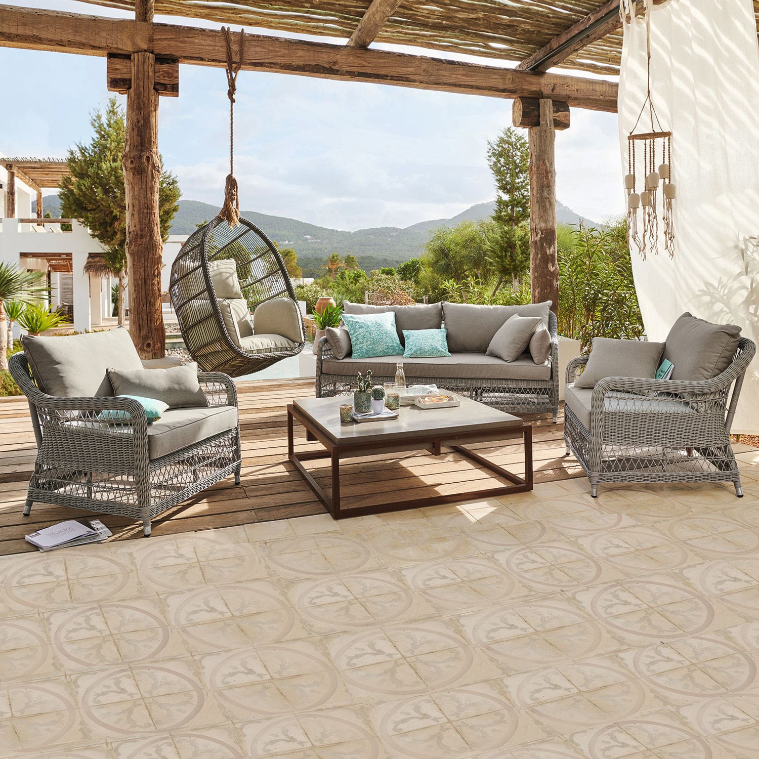 Sitzgruppe Tanaiste Gartenmöbel-Set aus grauem Rattan mit Polstern und hängendem Korbsessel auf der Terrasse mit Bergsicht