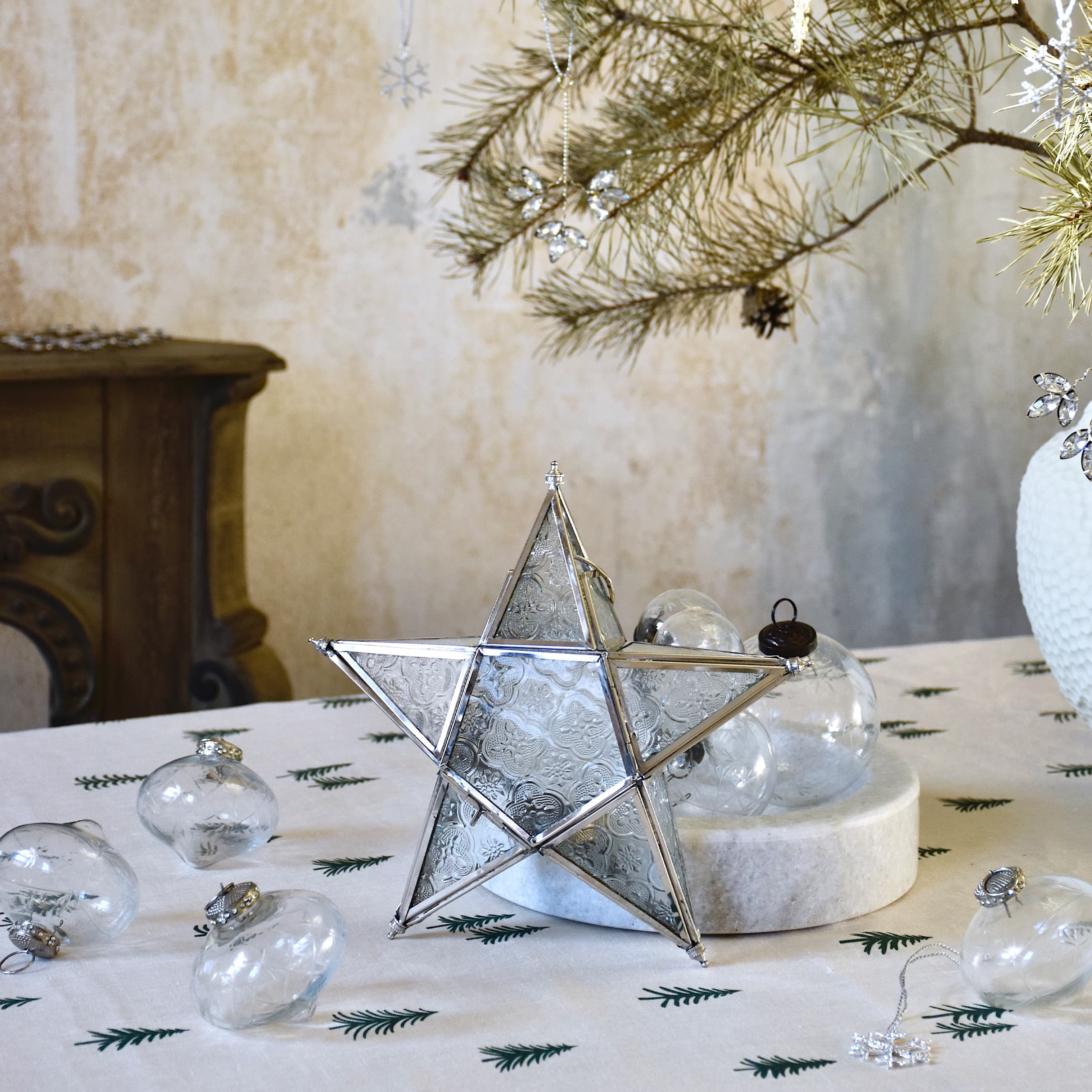 Dekorativer Stern aus Glas und Metall auf Weihnachtstisch mit transparenten Kugeln