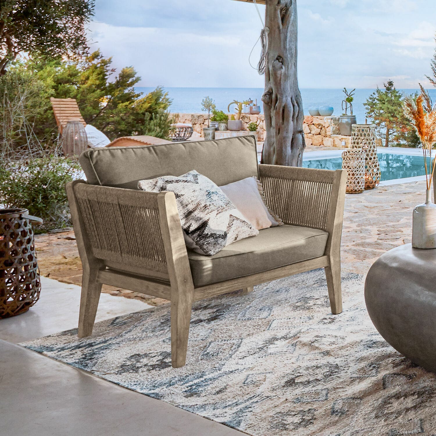 Sessel FSC®-100% Biarritz Outdoor-Sofa aus Holz und beigem Stoff auf der Terrasse mit Meerblick