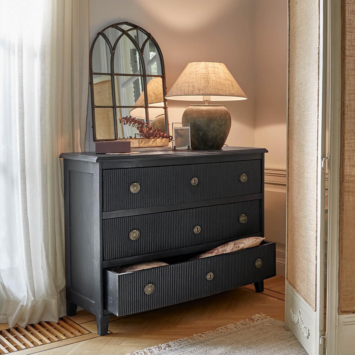 Schwarze Holzkommode mit drei Schubladen und Metallgriffen in klassischem Interieur