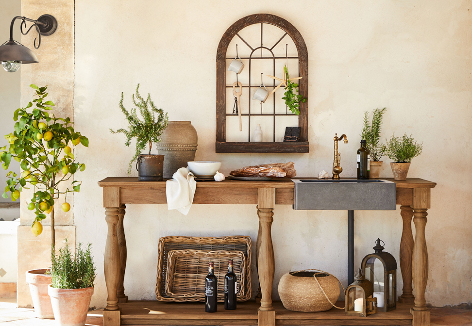 Holztisch mit Betonschale und Messingarmatur im mediterranen Stil mit Pflanzen und Dekorationen