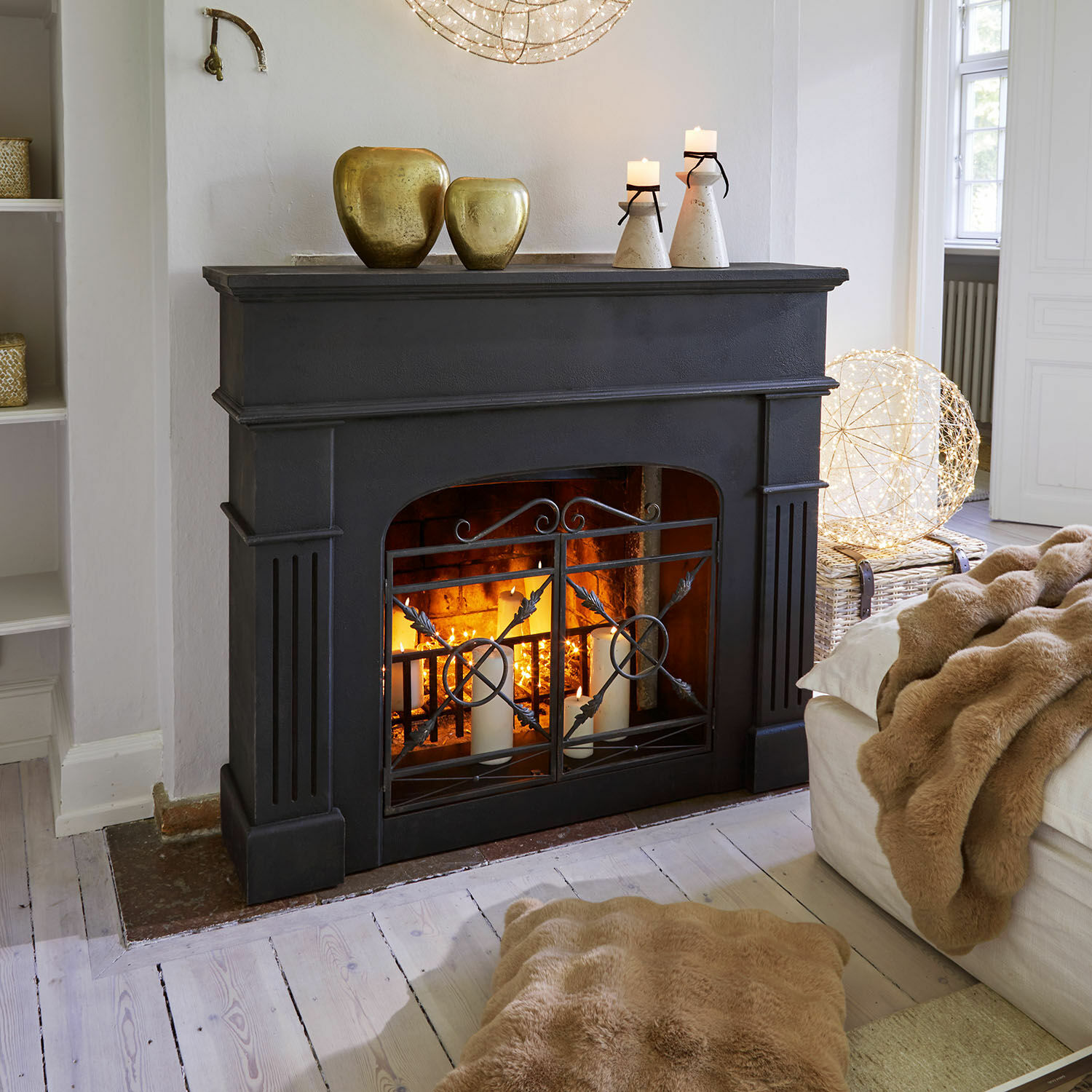 Kaminkonsole Hollowfield Schwarzer Kamin mit Metallgitter und Kerzen, dekoriert mit goldenen Vasen, gemütliches Wohnzimmer mit Felldecke