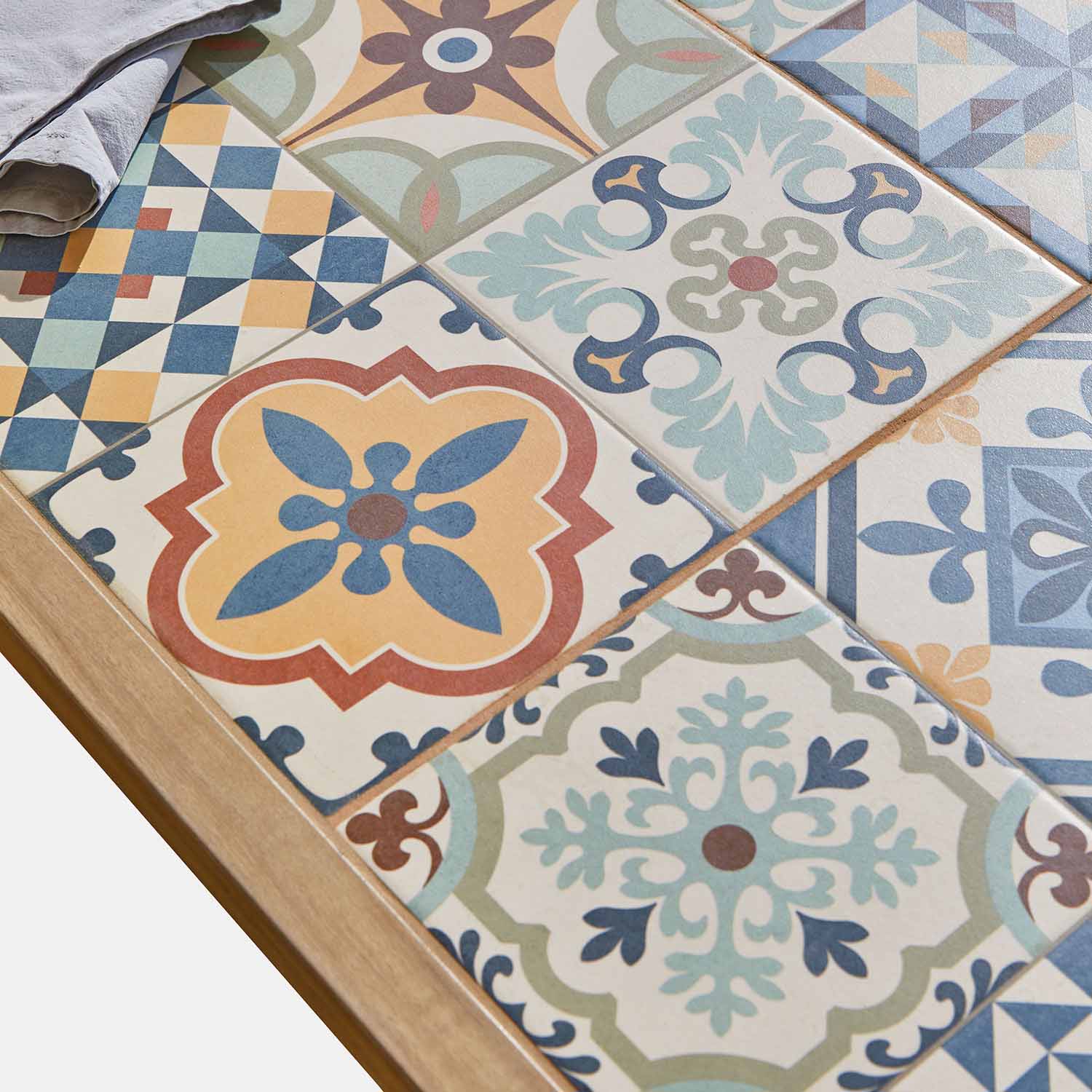 Bunte Keramikfliesen mit geometrischen und floralen Mustern auf Holztisch, Wohnraumdekoration