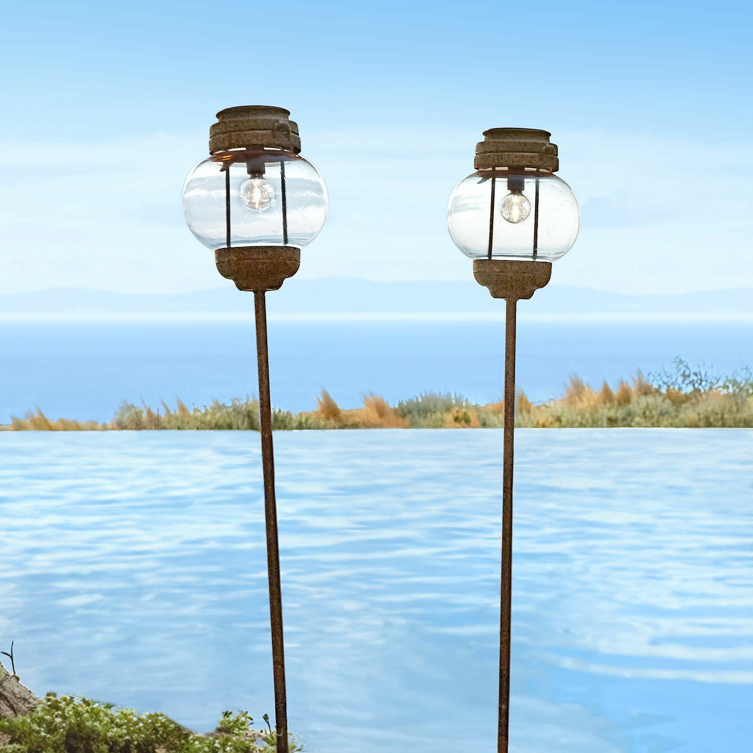 Solar-Laterne 2er Set Nayalif Zwei Gartenlampen aus Glas und rostigem Metall beim Pool mit Meerblick