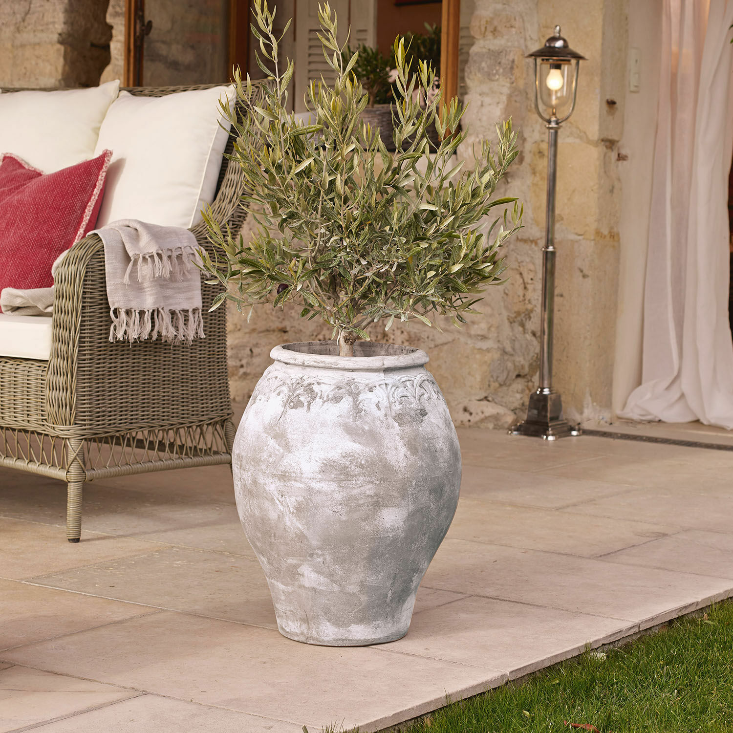 Übertopf Donneville Grosse graue Keramikvase mit Pflanze auf Terrasse neben Korbsessel mit Kissen