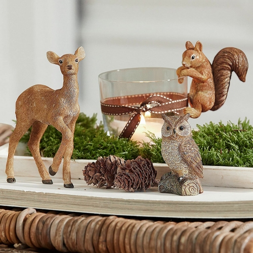 Dekorative Tierfiguren aus Holz mit Glaswindlicht und Kerze auf grünem Moos, natürliche Tischdekoration