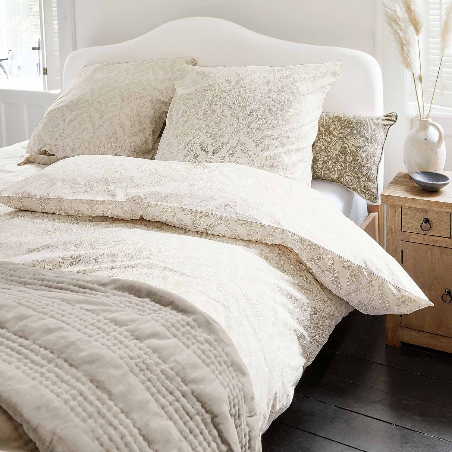 Helle Baumwollbettwäsche mit feinem Pflanzenmuster und weiche Decke in gemütlichem Schlafzimmer