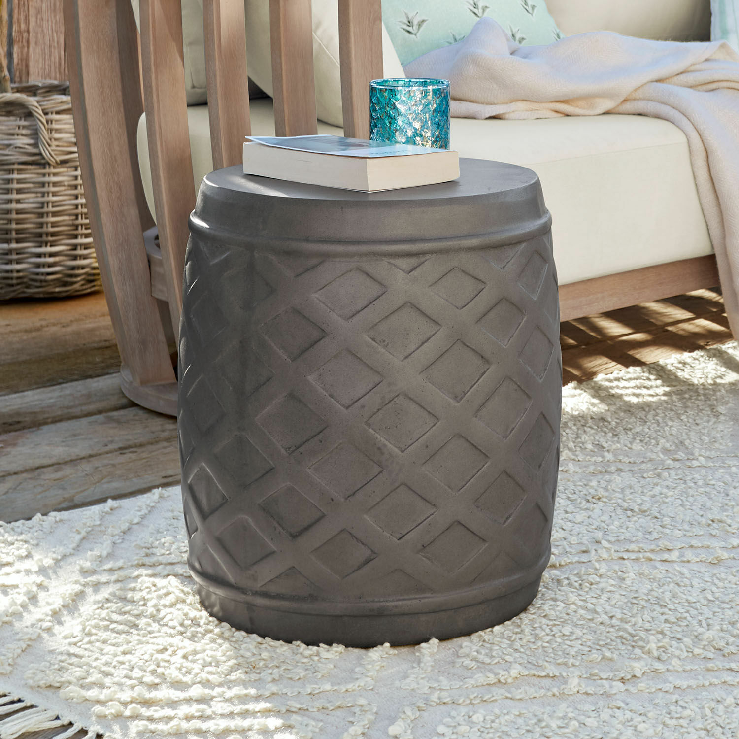 Hocker Plévin Grauer Beistelltisch aus Beton mit geometrischem Muster auf Teppich im Wohnzimmer mit Holzmöbeln.