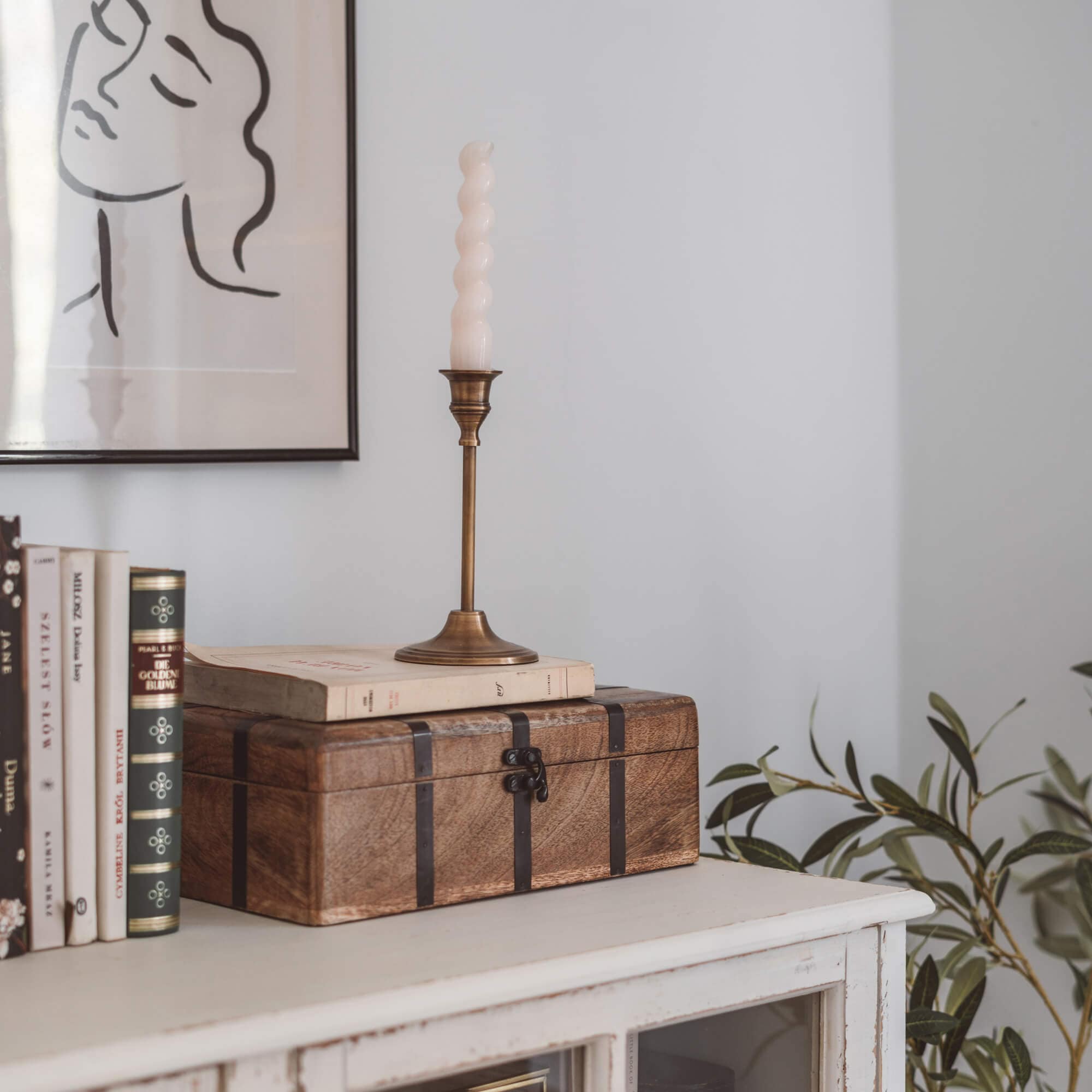 Braune Holzkiste mit Metallbändern auf weissem Sideboard mit Büchern und Kerze
