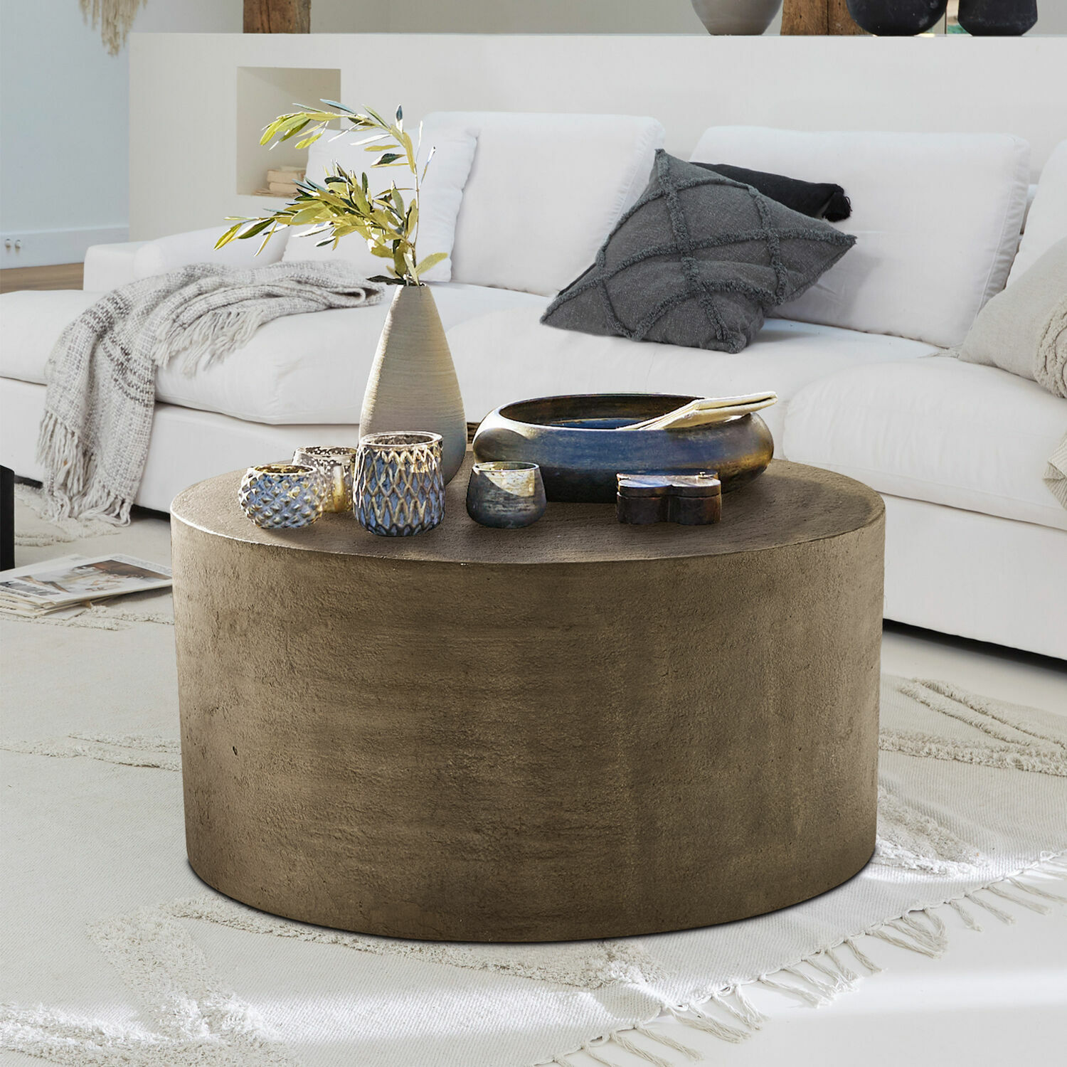 Runder Couchtisch aus braunem Beton auf hellem Teppich im modernen Wohnzimmer mit weissem Sofa