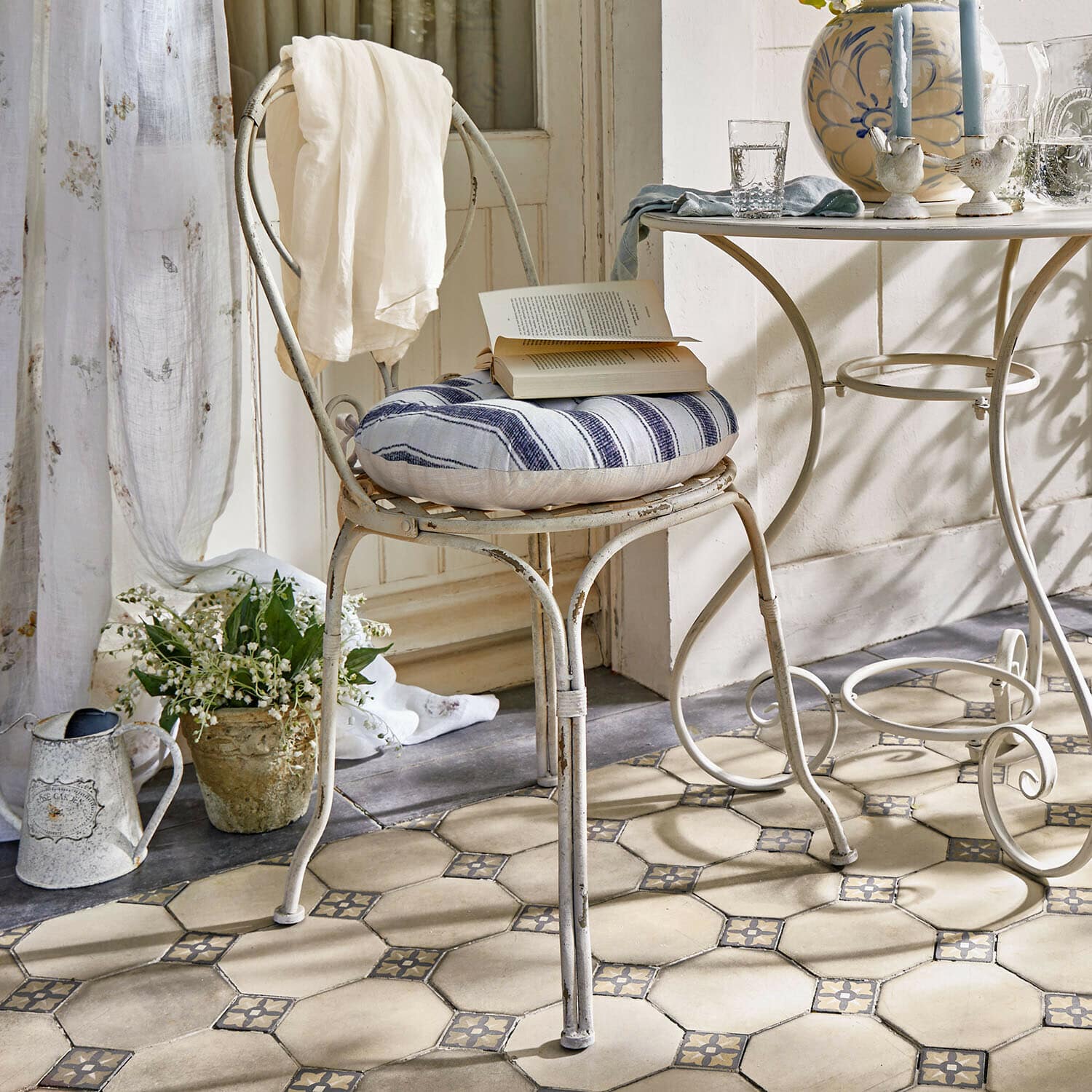Stuhl Aube Vintage Metallstuhl mit blau-weiß gestreiftem Kissen und weissem Tuch im hellen Raum mit Fliesenboden