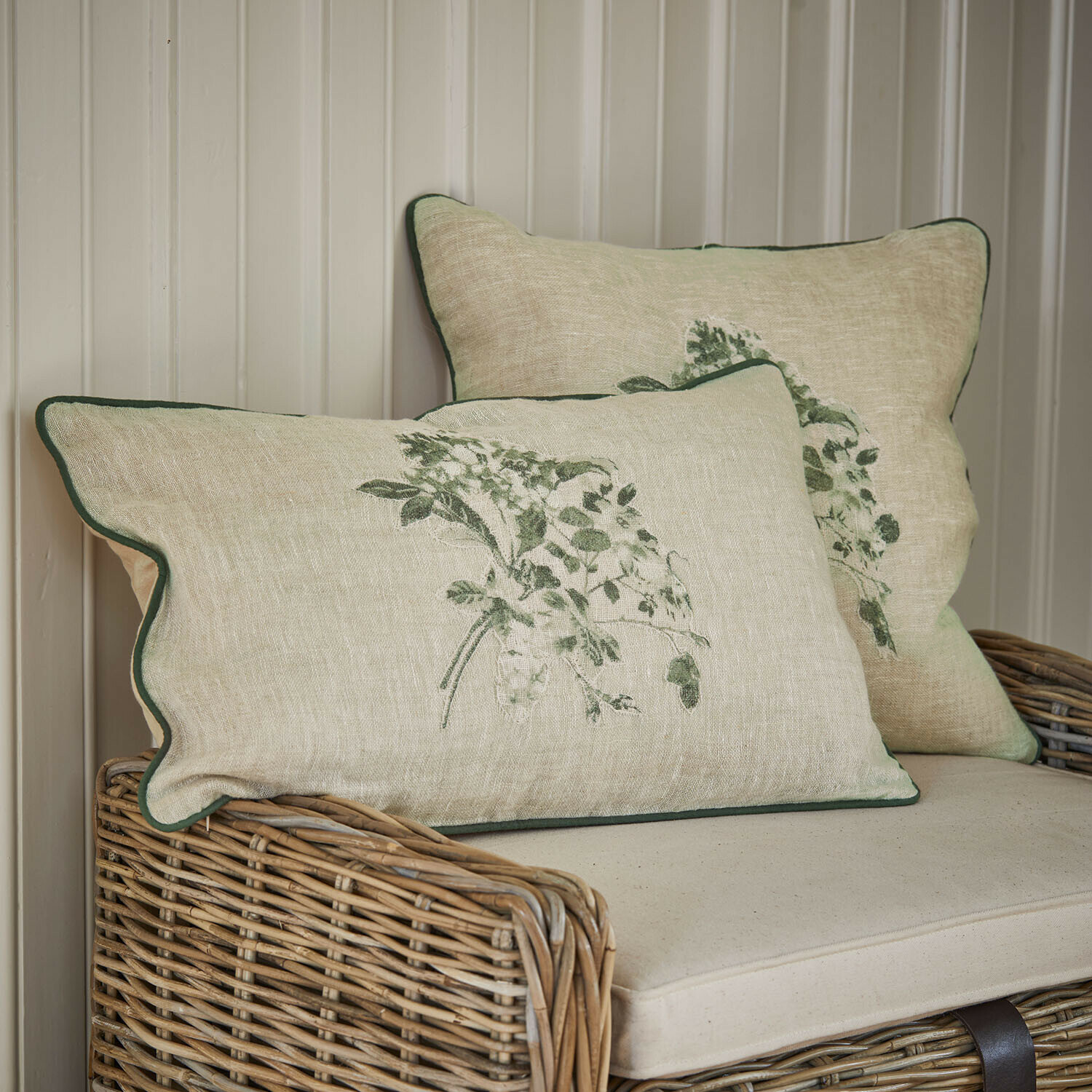 Kissenhülle 2er Set Chantrelle Beige Leinenkissen mit grünem Pflanzenmuster und grünem Rand auf Rattansofa