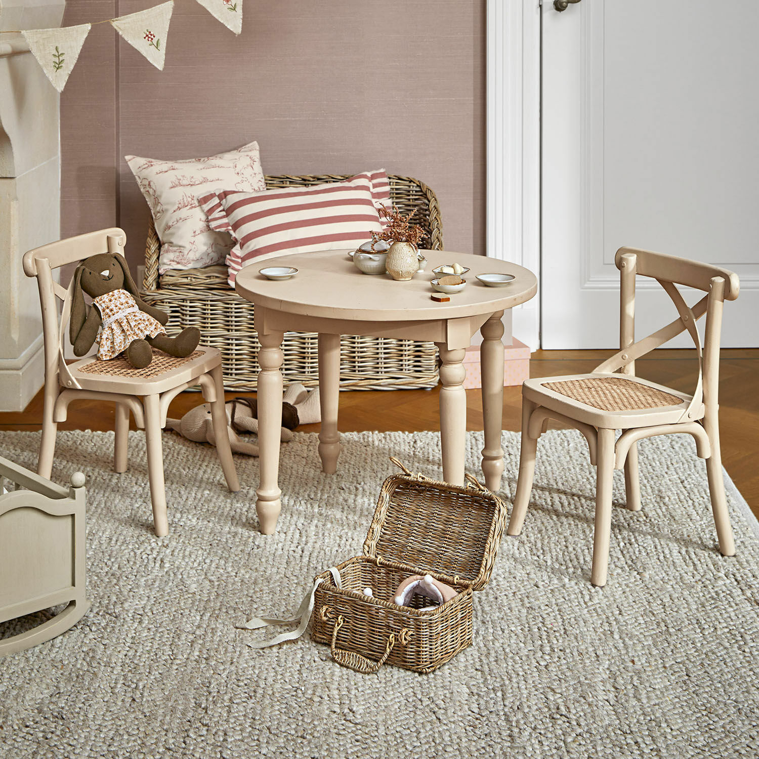 Kindersitzgruppe Sourila Beiger Holztisch mit zwei Stühlen und geflochtenen Sitzen in Kinderzimmer mit Spielzeug und Teppich
