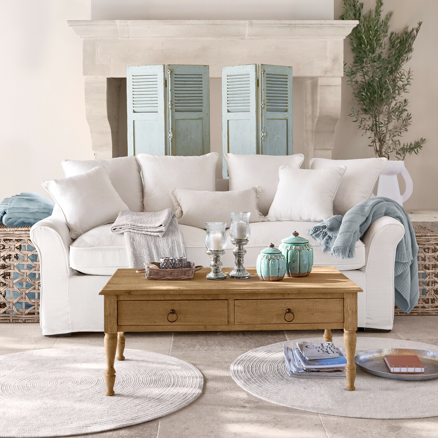 Beiges Sofa mit Kissen und Holzcouchtisch mit Dekoration in hellem Wohnzimmer mit Kamin