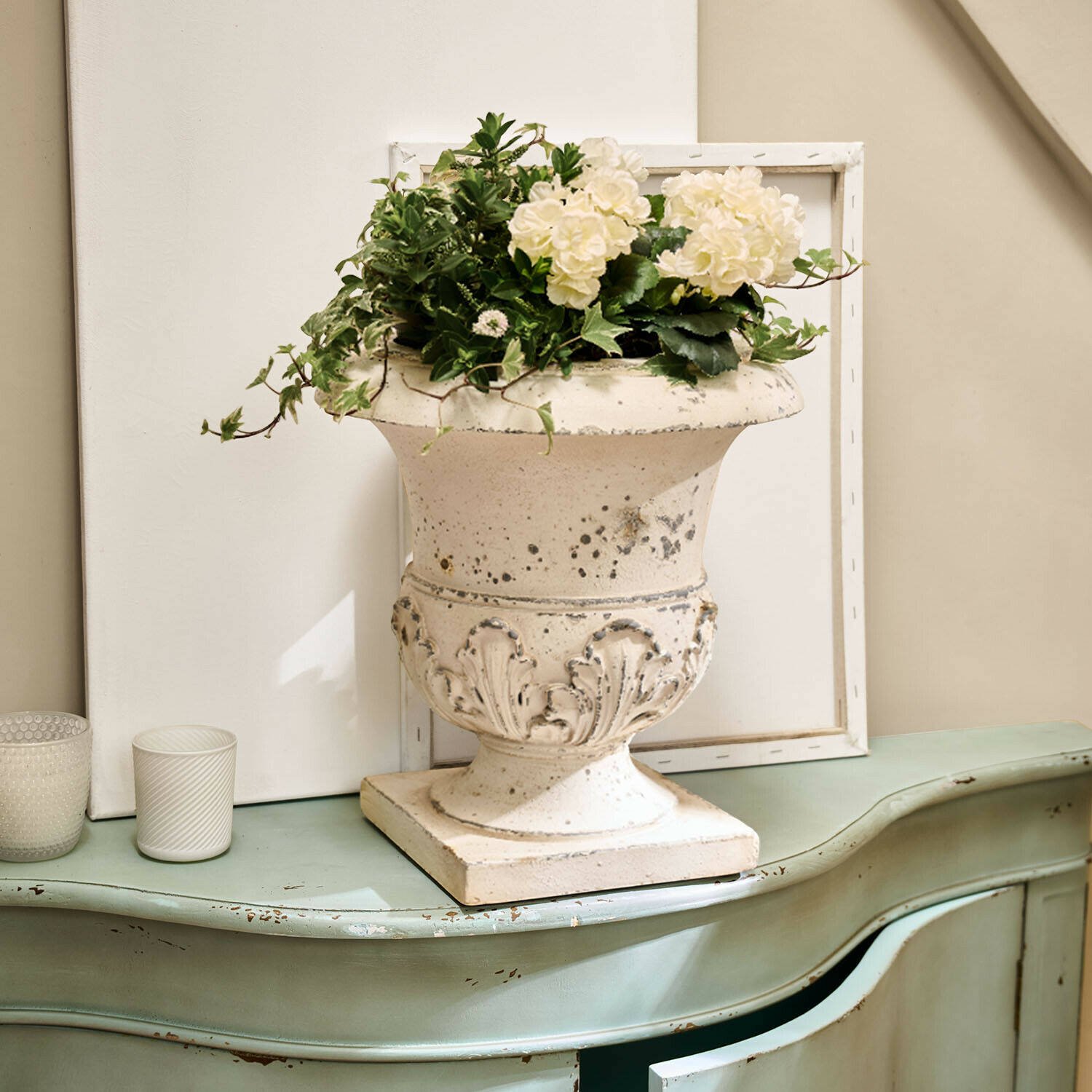Amphore Lorianza Weisse Keramikvase mit Pflanzenarrangement auf grünem, antik wirkendem Vintage-Kommode