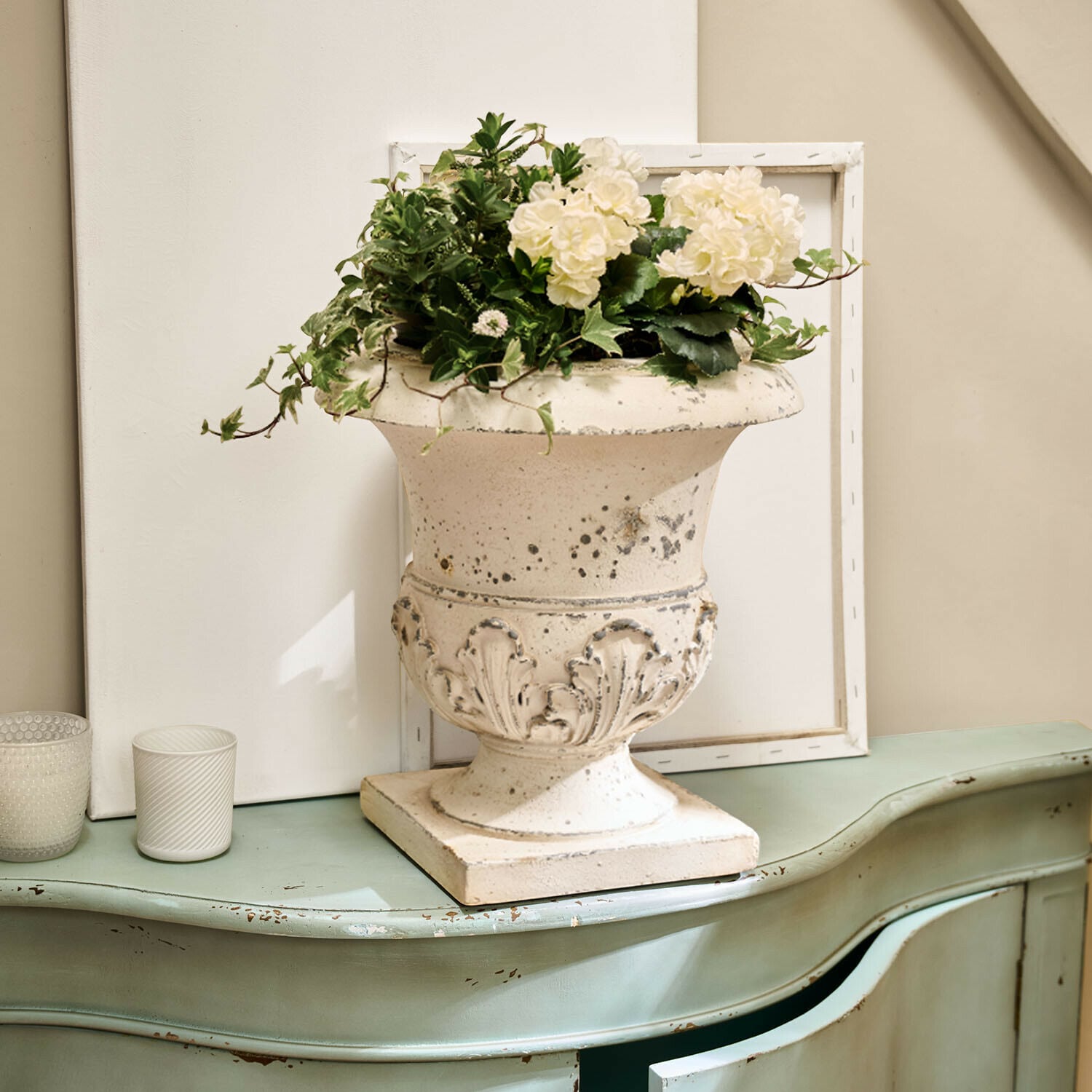 Amphore Lorianza Weisse Keramikvase mit Pflanzenarrangement auf grünem, antik wirkendem Vintage-Kommode