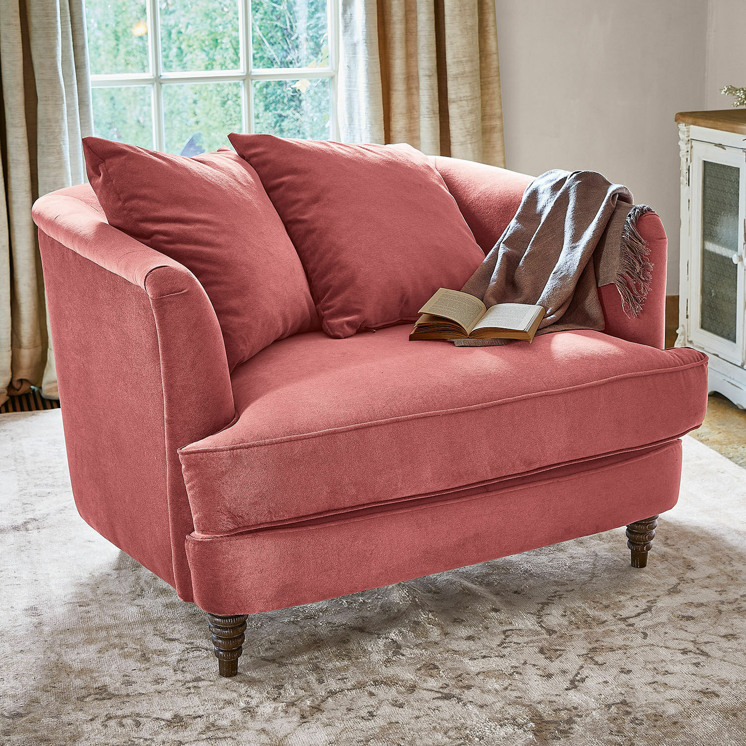 Sessel Etueffont Rosa Sofa aus weichem Stoff mit Kissen und grauem Plaid auf hellem Teppich im Wohnzimmer