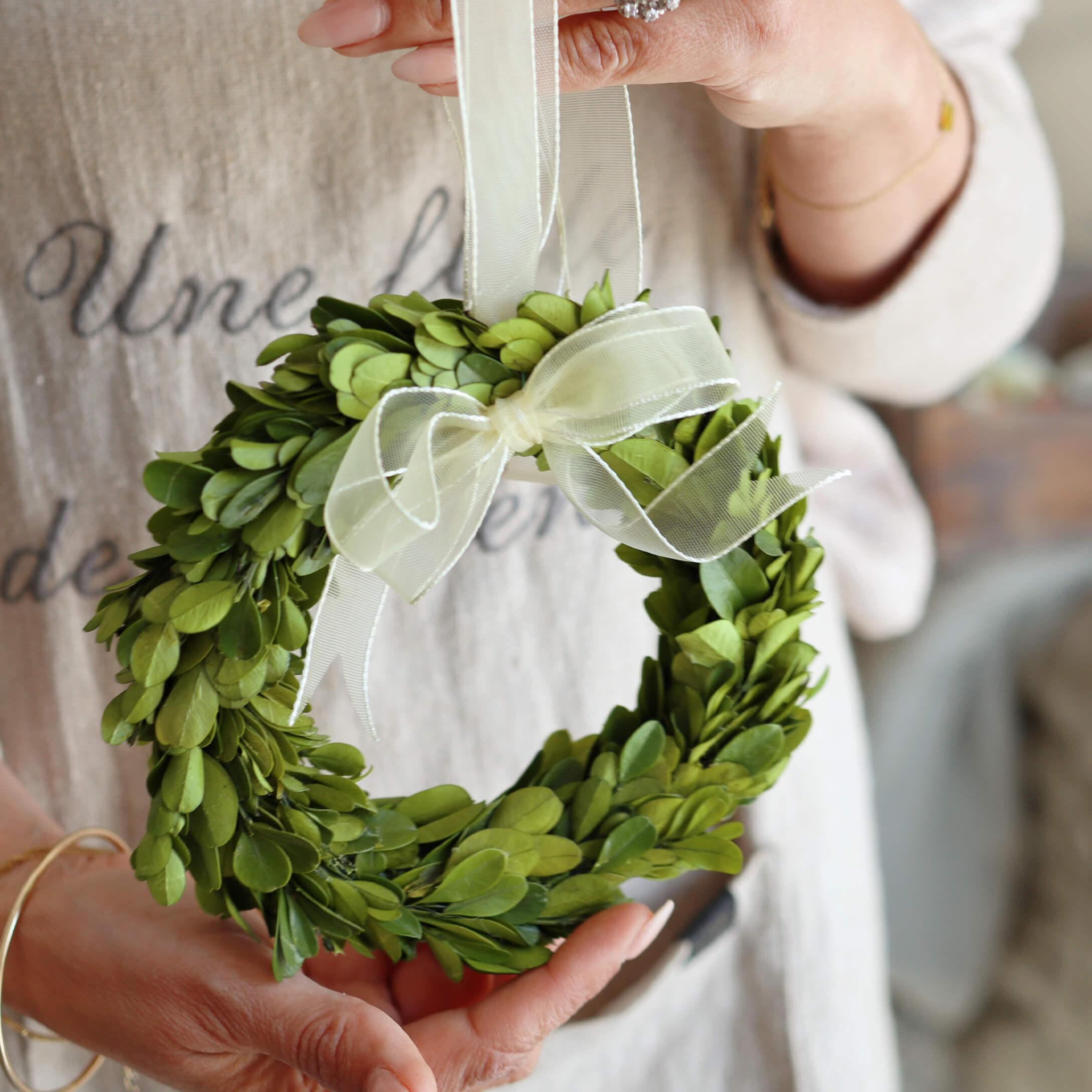 Kleiner grüner Kranz aus Blättern mit weisser Schleife, Dekoration für Zuhause oder Tür
