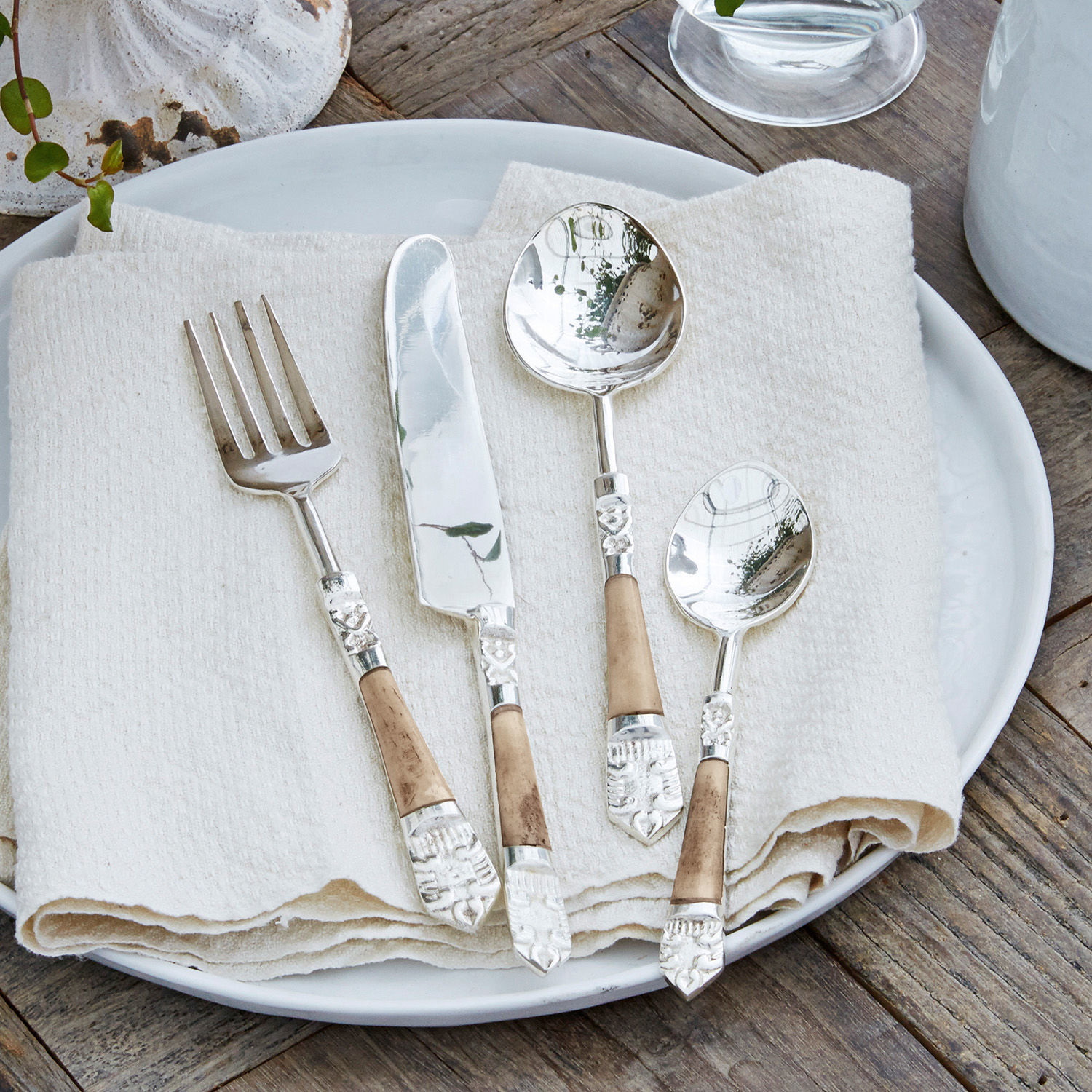 Besteck 4er Set Ferrette Besteckset mit Metallteilen und Holzgriffen auf weissem Teller mit Leinenserviette