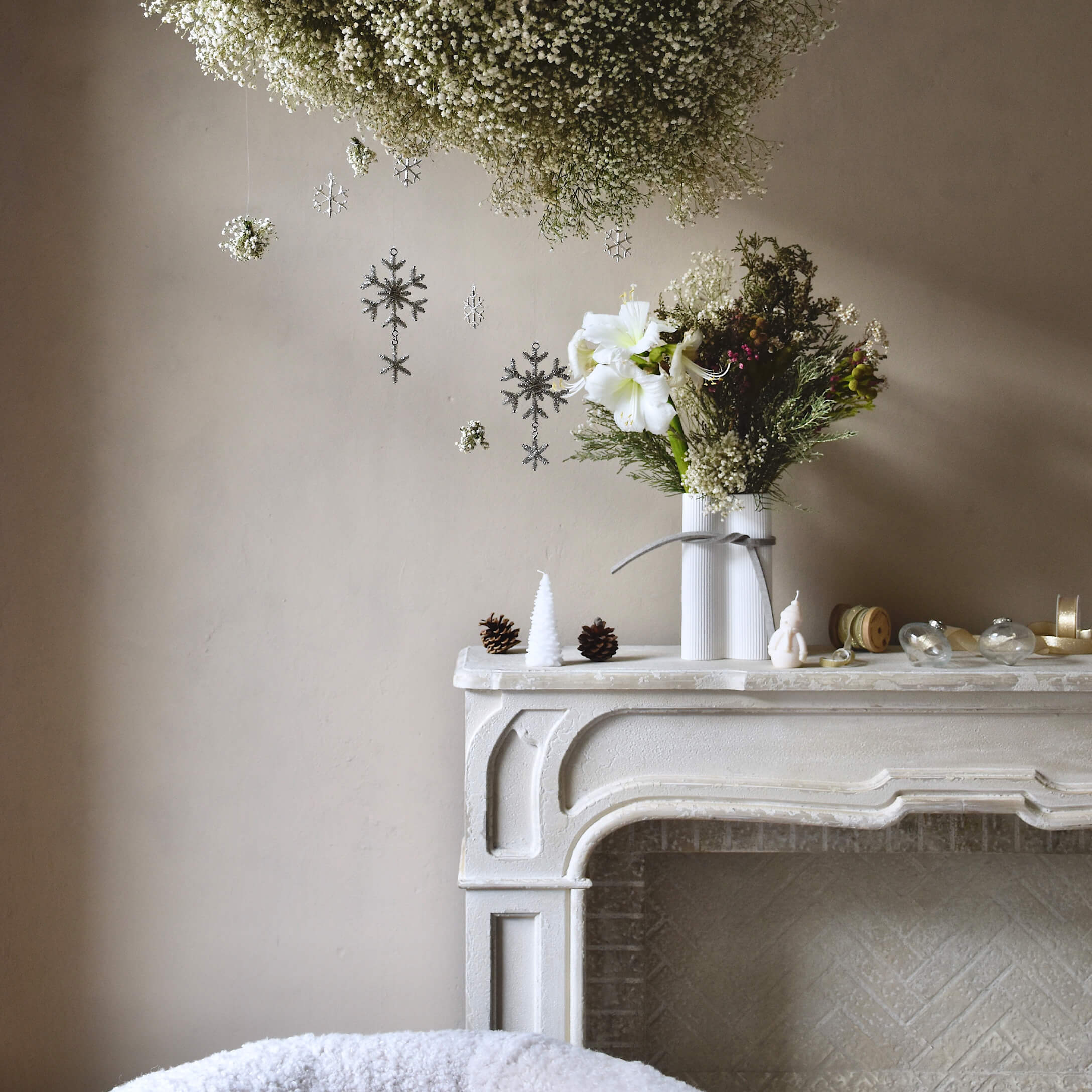Weißer dekorativer Kamin mit Vase und Blumen, Weihnachtsdekoration mit Zapfen und Kerzen