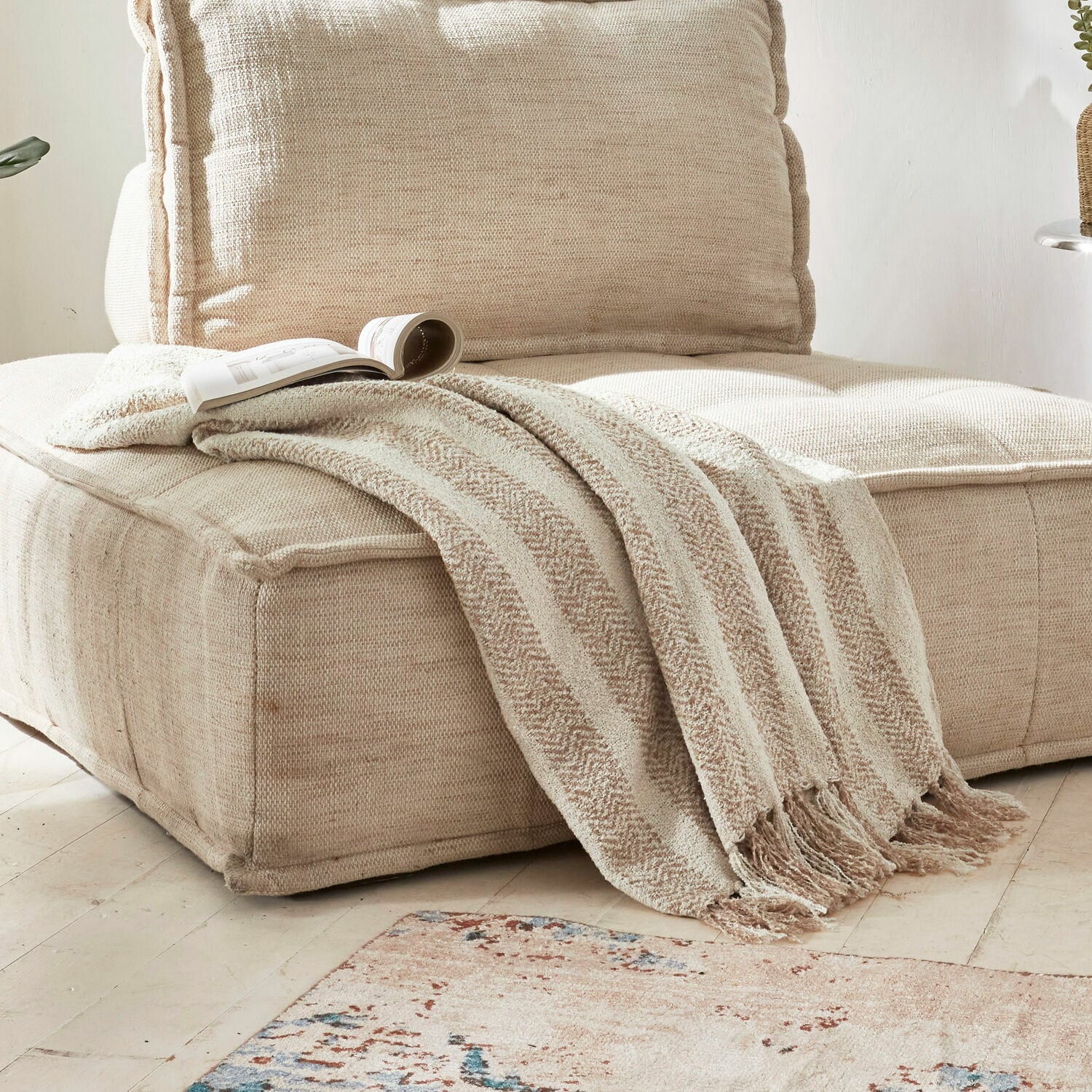 Plaid Aldan Beige, weiche Decke mit Fransen auf beigem Stoffsofa in hellem Wohnzimmer