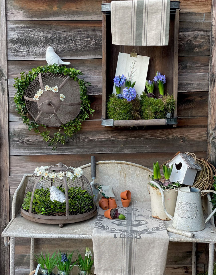 Rustikaler Metall-Gartentisch mit grünen Pflanzen und blauen Blüten als Dekoration