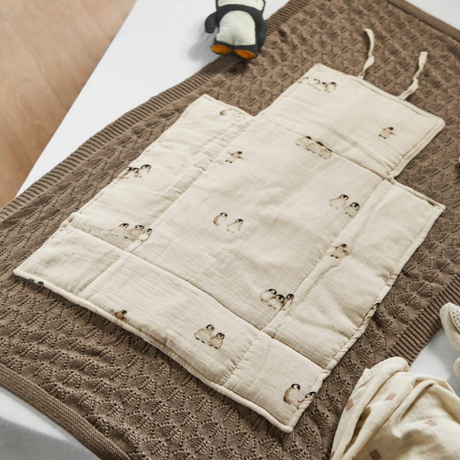Wickelunterlage Jocienne Beige Baumwoll-Krabbeldecke für Kinder mit Pinguin-Motiv auf brauner Strickdecke, Babyzubehör