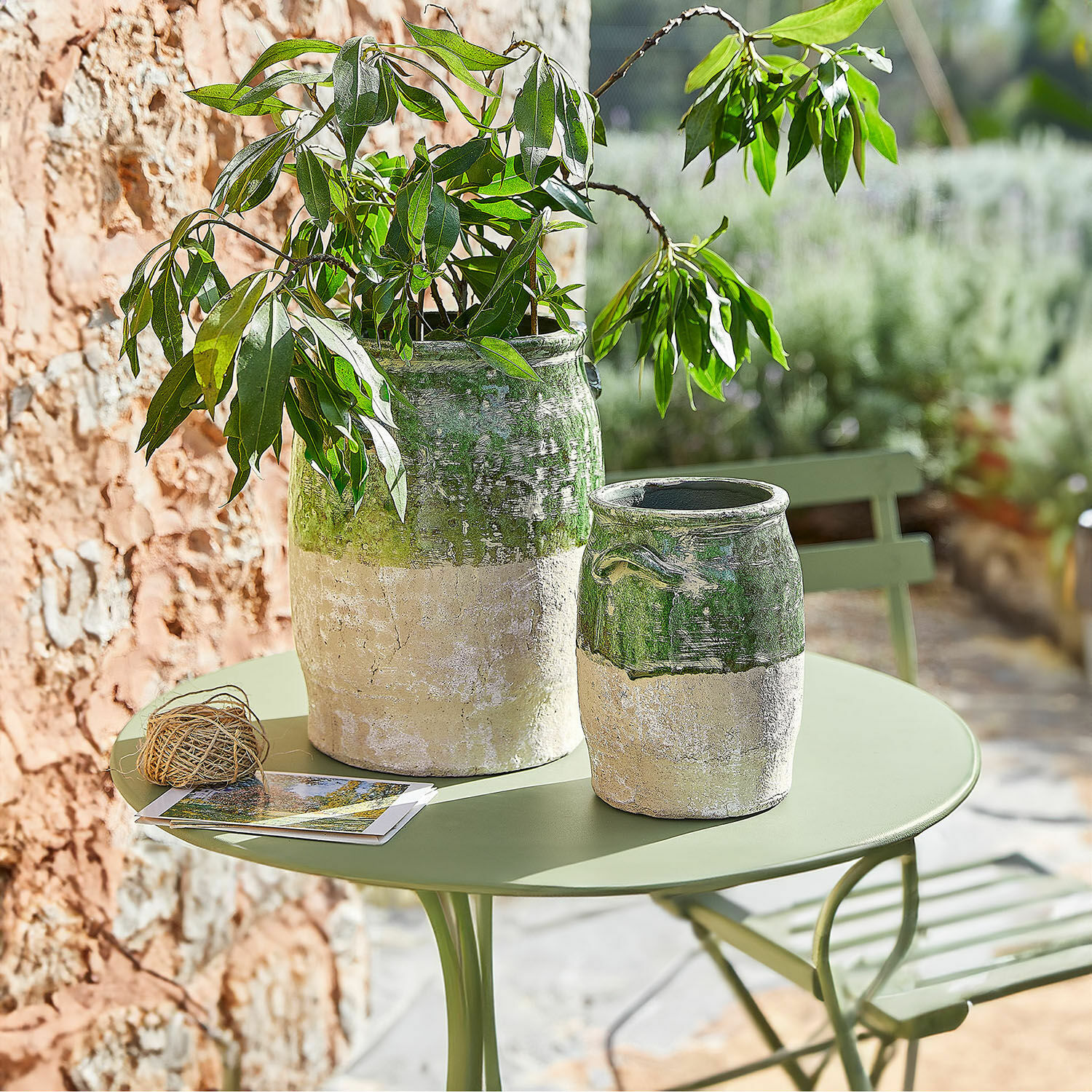 Vase 2er Set Reefton Zwei grün-beige Keramikvasen auf grünem Gartentisch mit Pflanze und Postkarten
